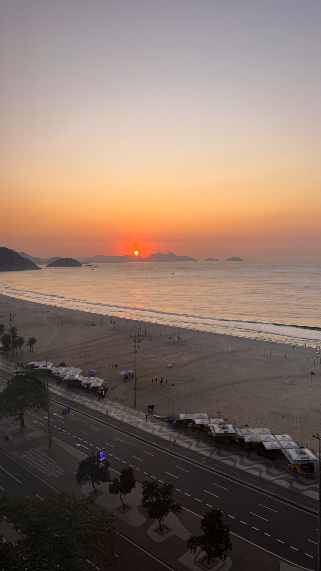 Orange sun setting beyond islands and Copacabana Beach
