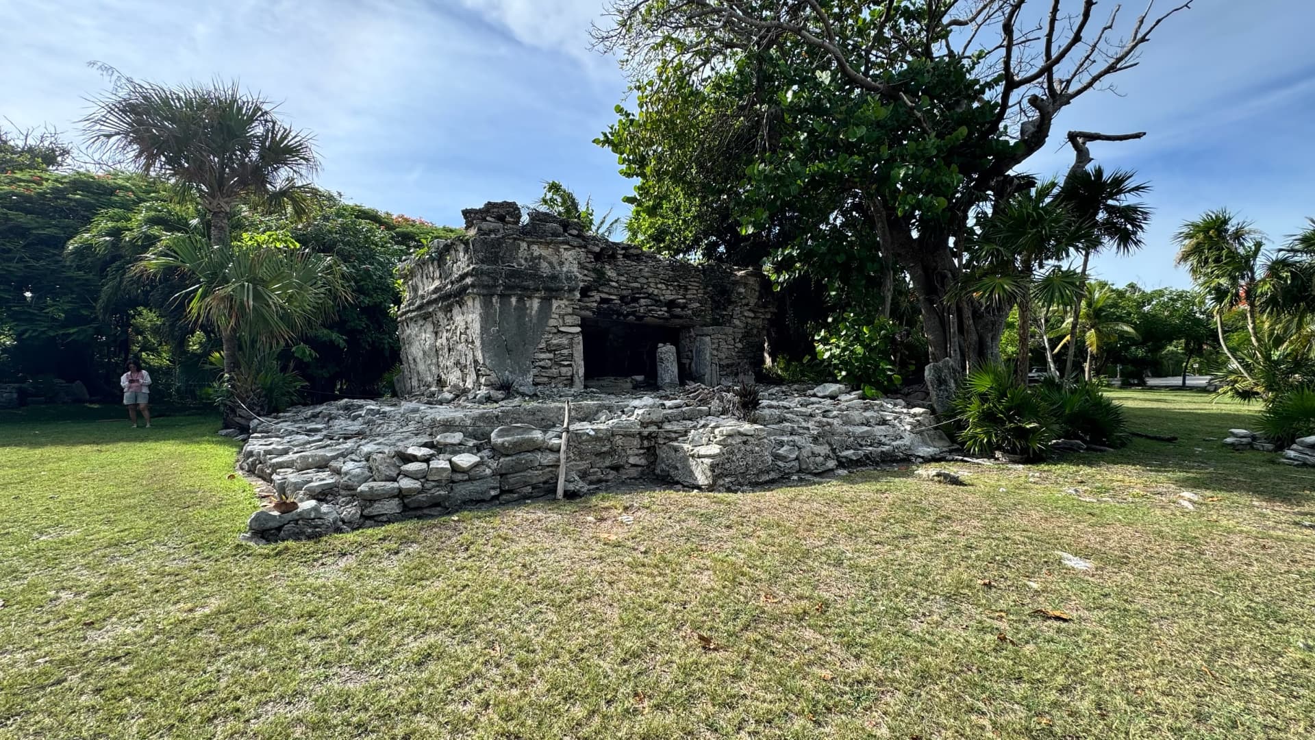 Small Maya structure surrounded by palms and lawn