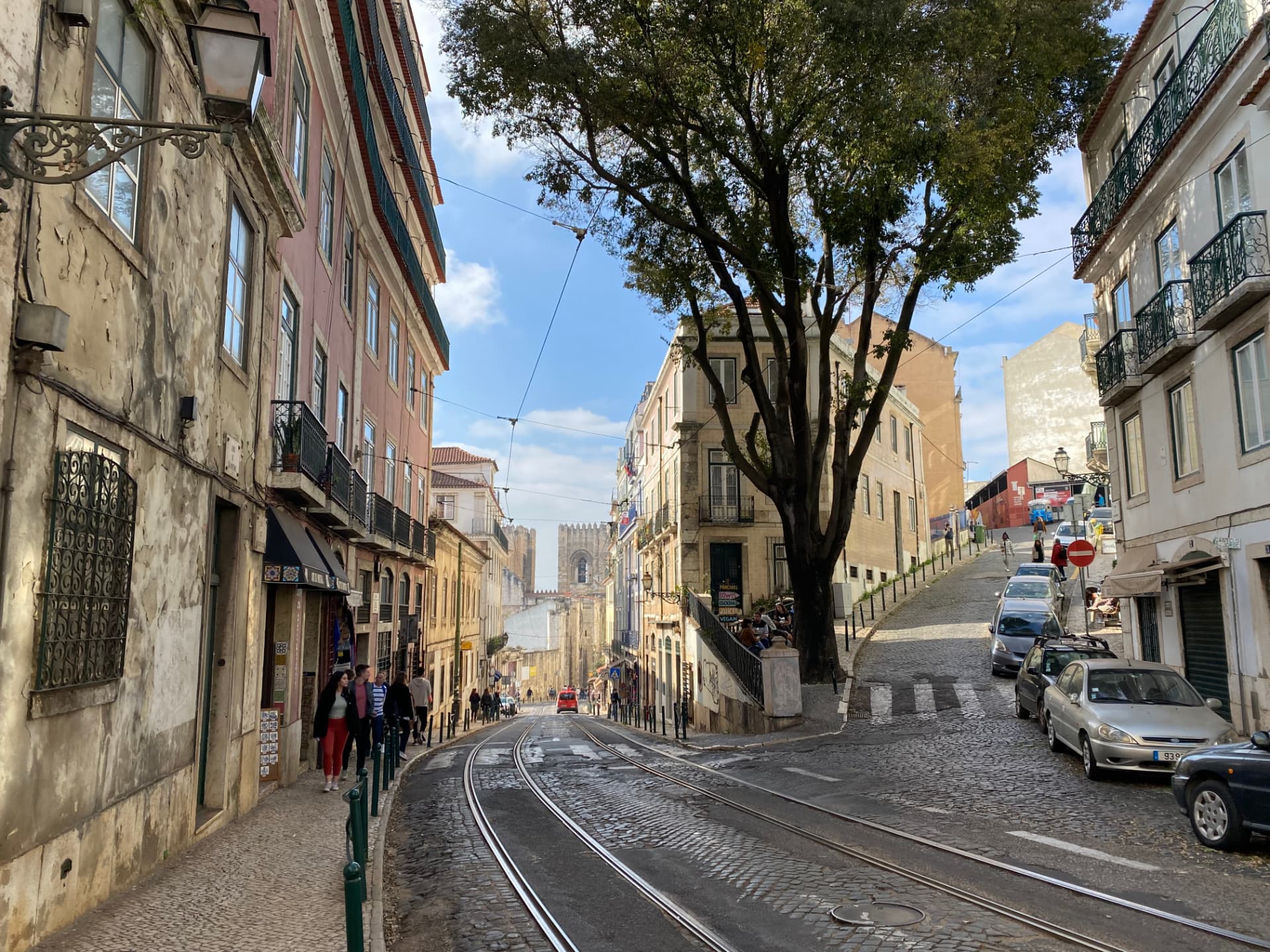 A narrow cobbled street with tram tracks winding between old buildings
