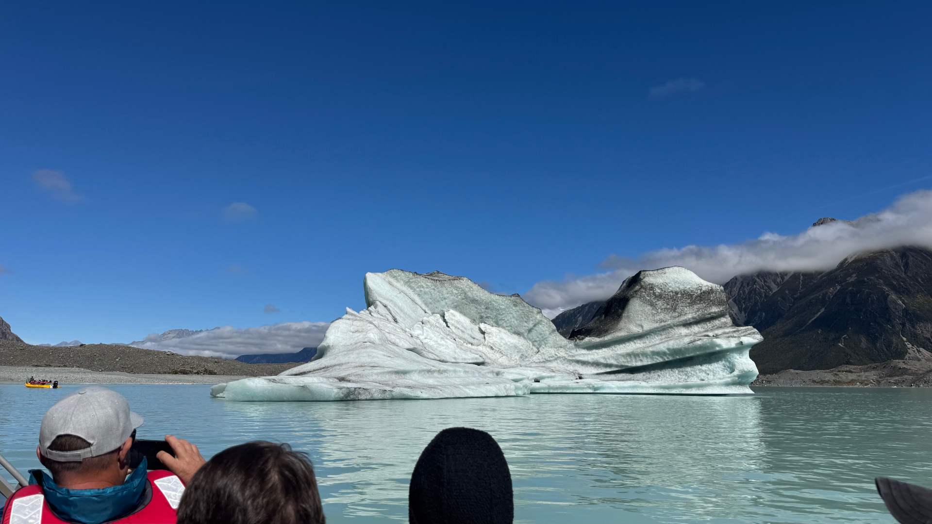Passengers photographing a huge grey and white iceberg resting in the still glacial lake