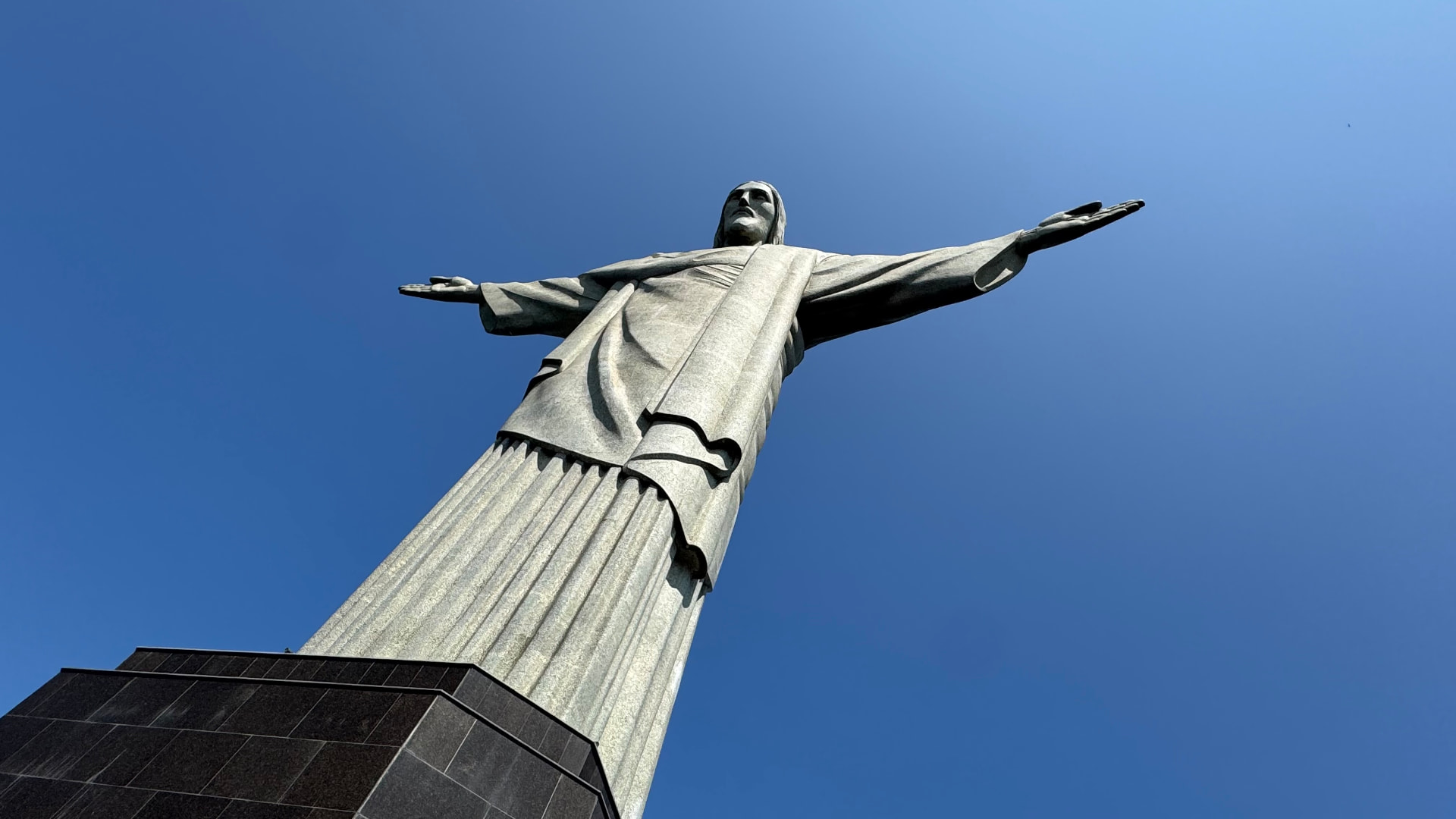 Low-angle view of Christ the Redeemer against a deep blue sky