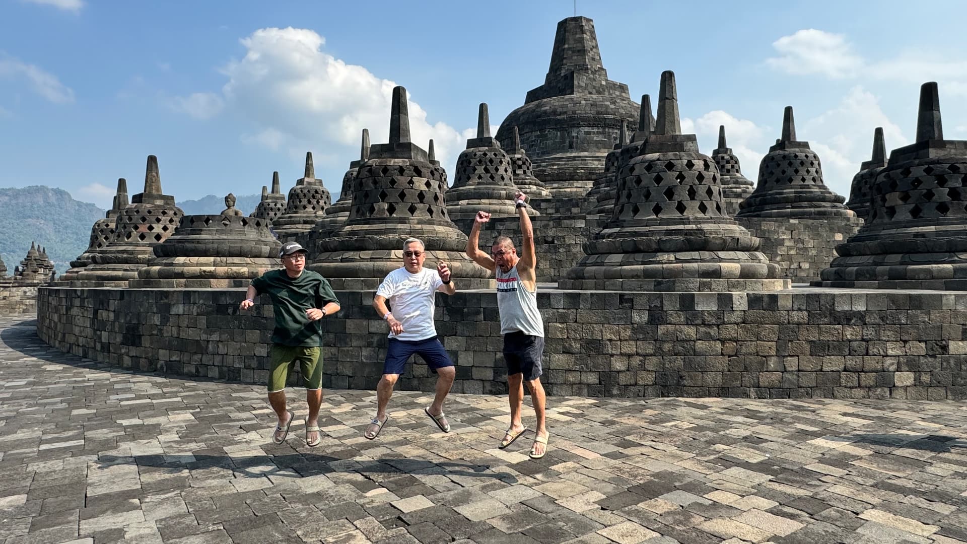 Friends jumping together in front of the stupas