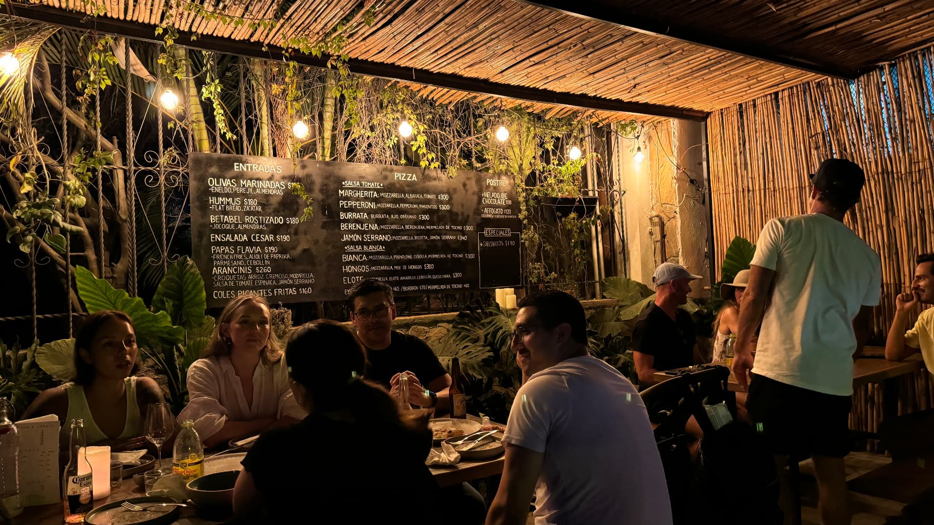 A lively open-air restaurant under bamboo and warm hanging lights