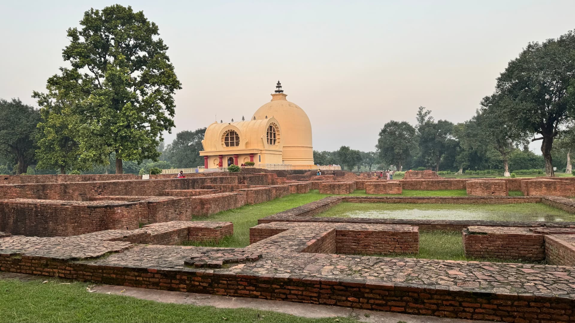 Ancient brick foundations with the Nirvana Temple beyond. — Kushinagar, Uttar Pradesh, India.