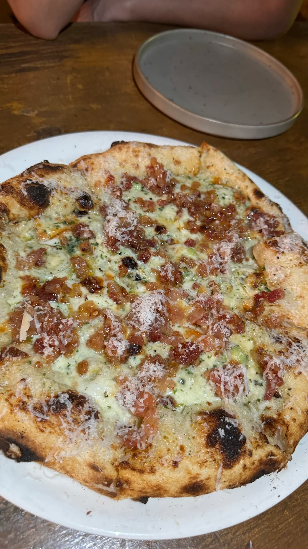 Wood-fired pizza with bacon, herbs, and melted cheese