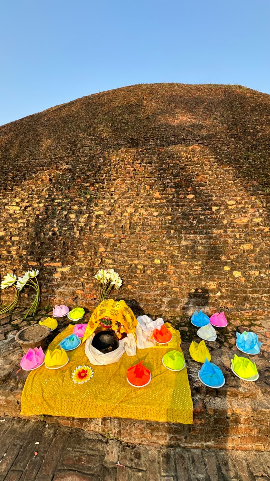 Flowers and offerings placed against the brickwork of Ramabhar Stupa. — Kushinagar, Uttar Pradesh, India.