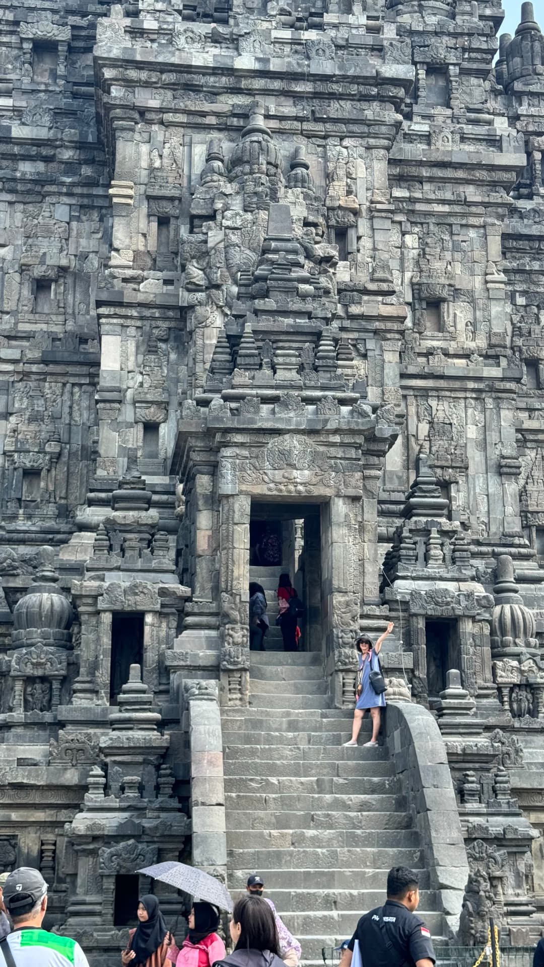Traveler waving from the steps of a carved temple entrance
