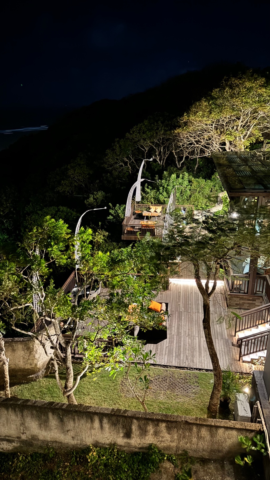Terraced treetop restaurant glowing against the dark hillside