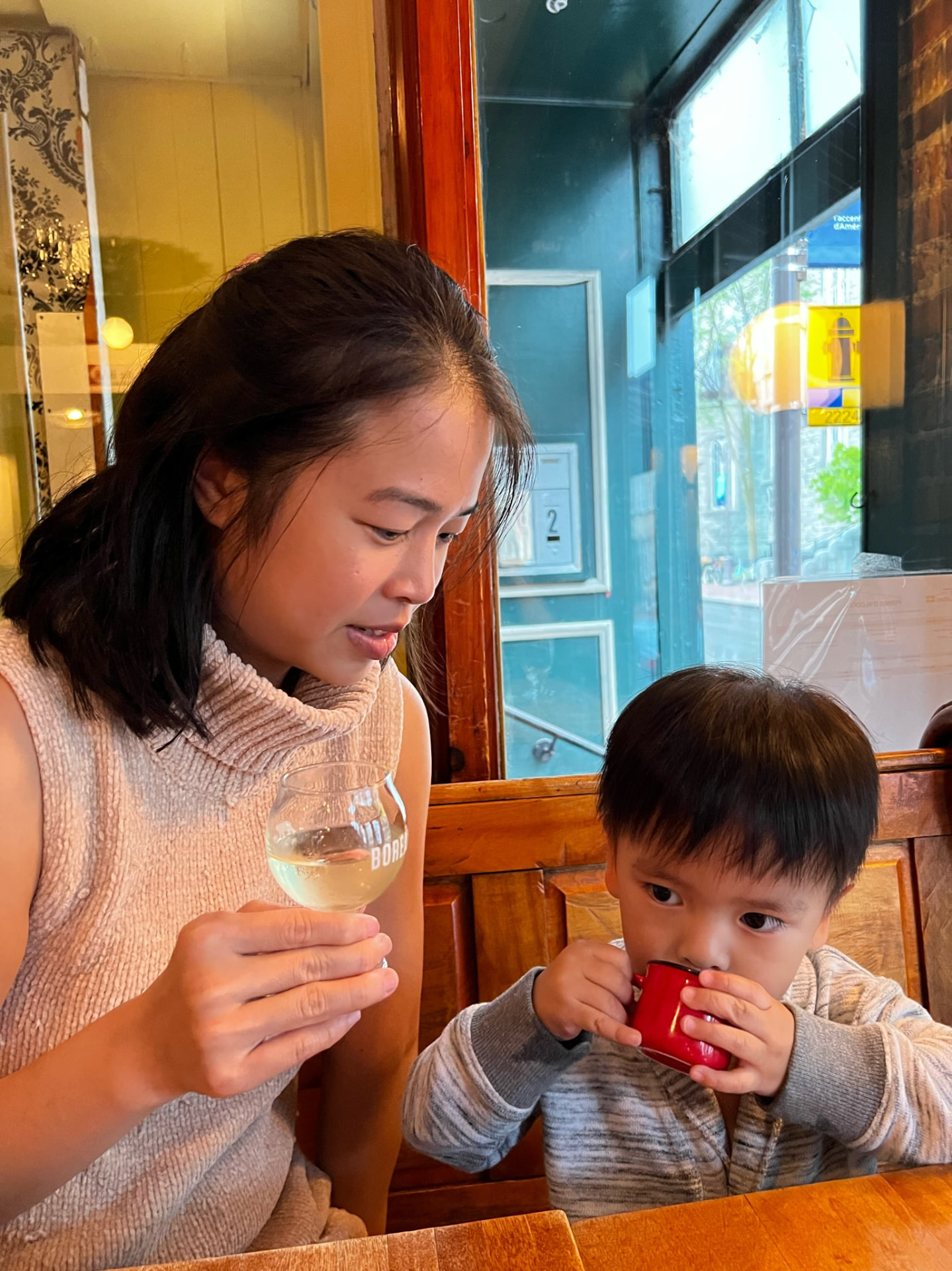 Mother and child sharing drinks at a wooden restaurant table