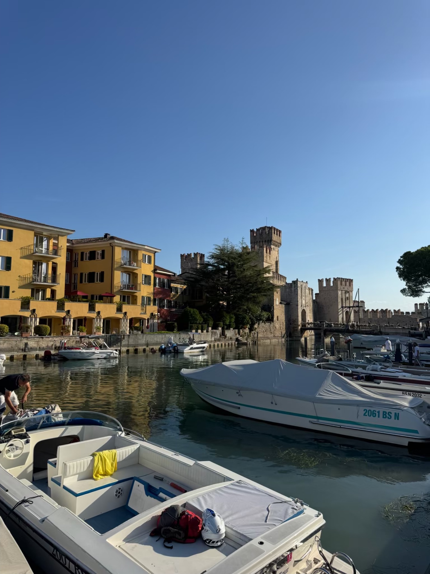 Boats moored beside the stone towers and walls of Scaligero Castle in Sirmione