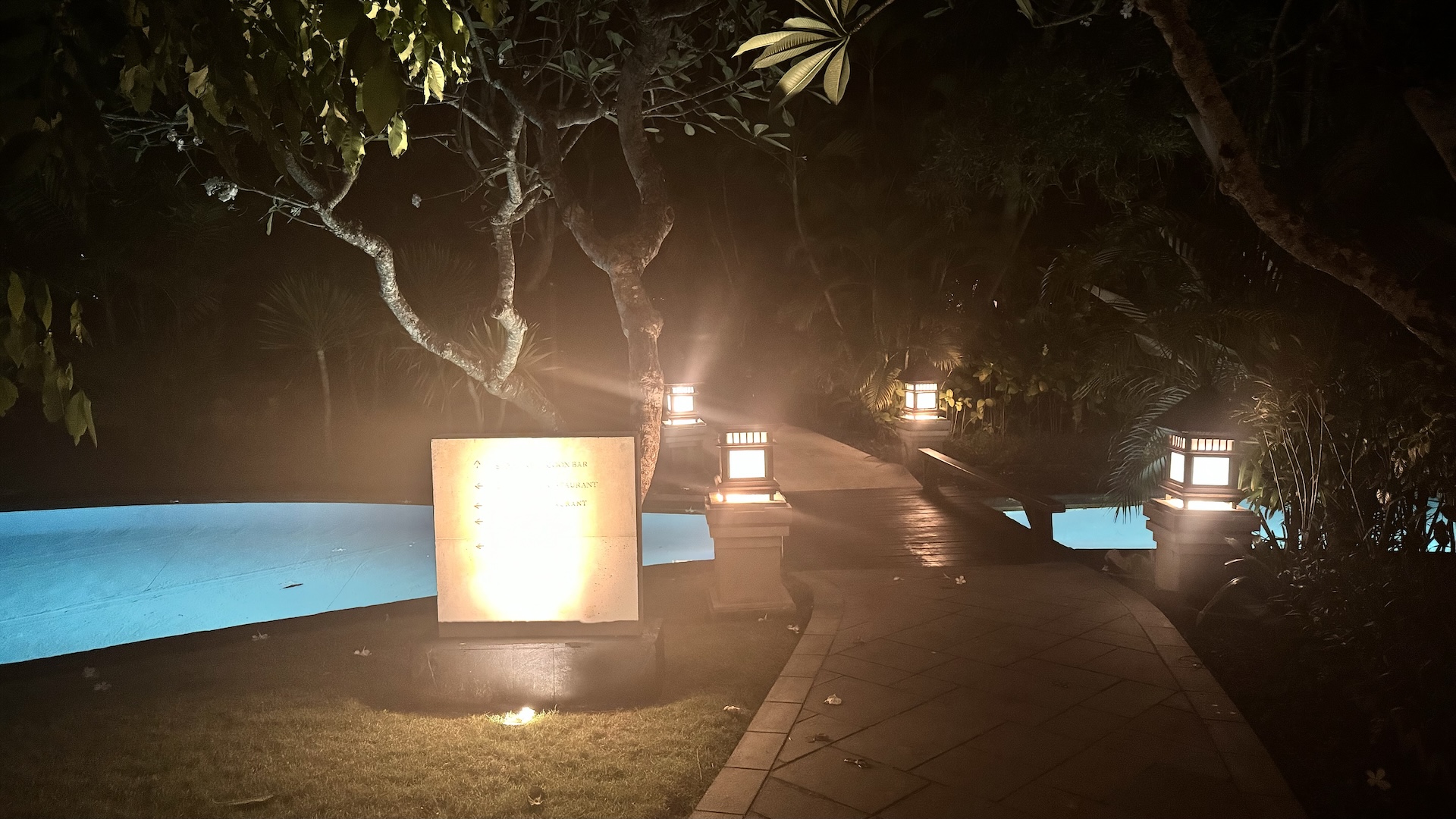 Lantern-lit pathway crossing the resort lagoon at night