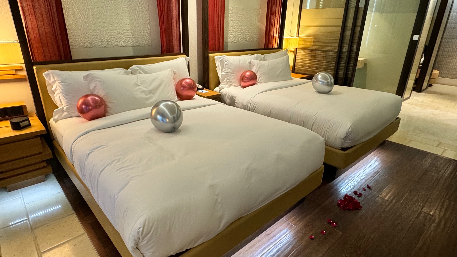 Twin beds decorated with balloons and rose petals