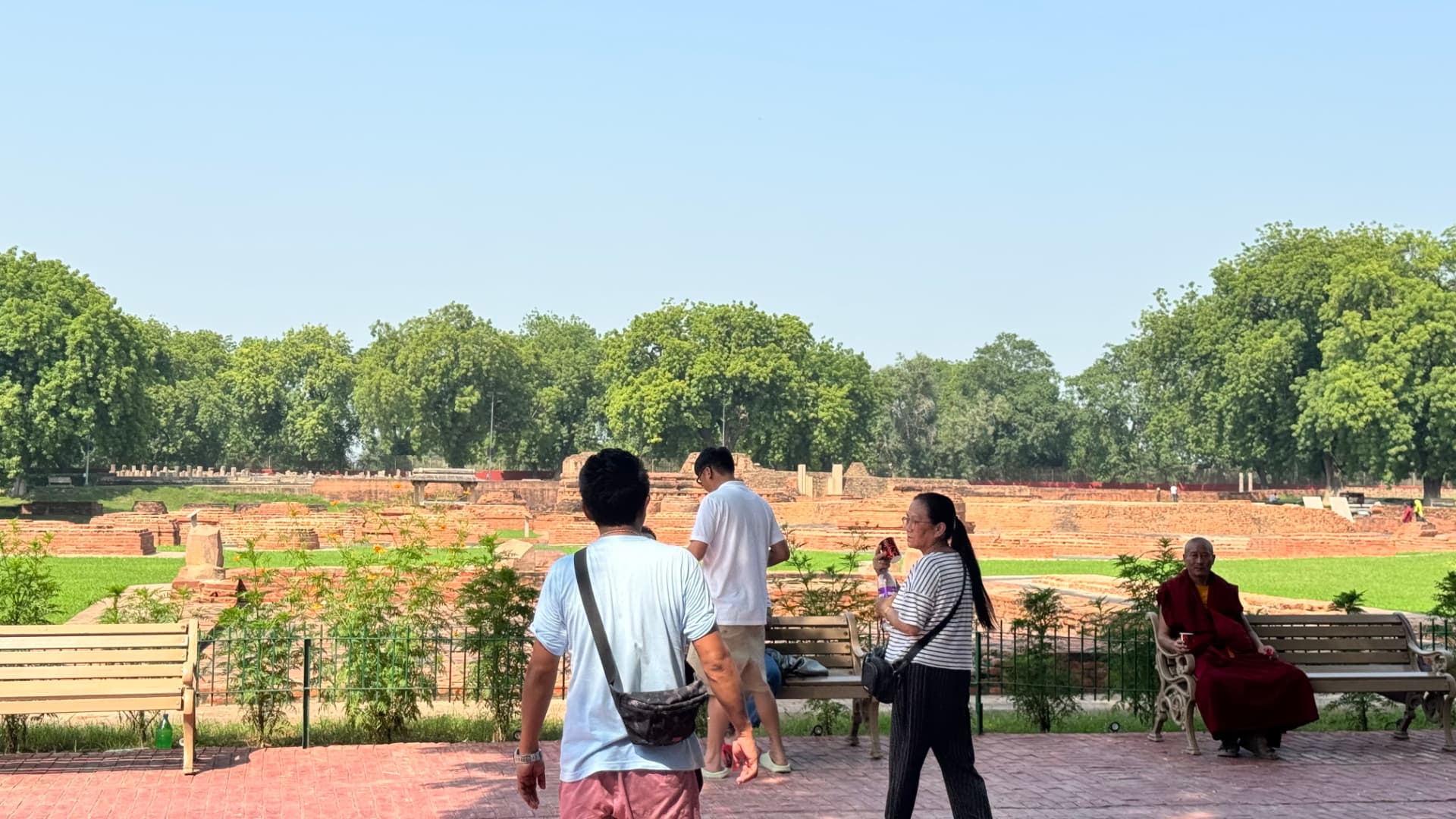 Visitors look across low brick foundations at the archaeological site. — Sarnath, Uttar Pradesh, India.