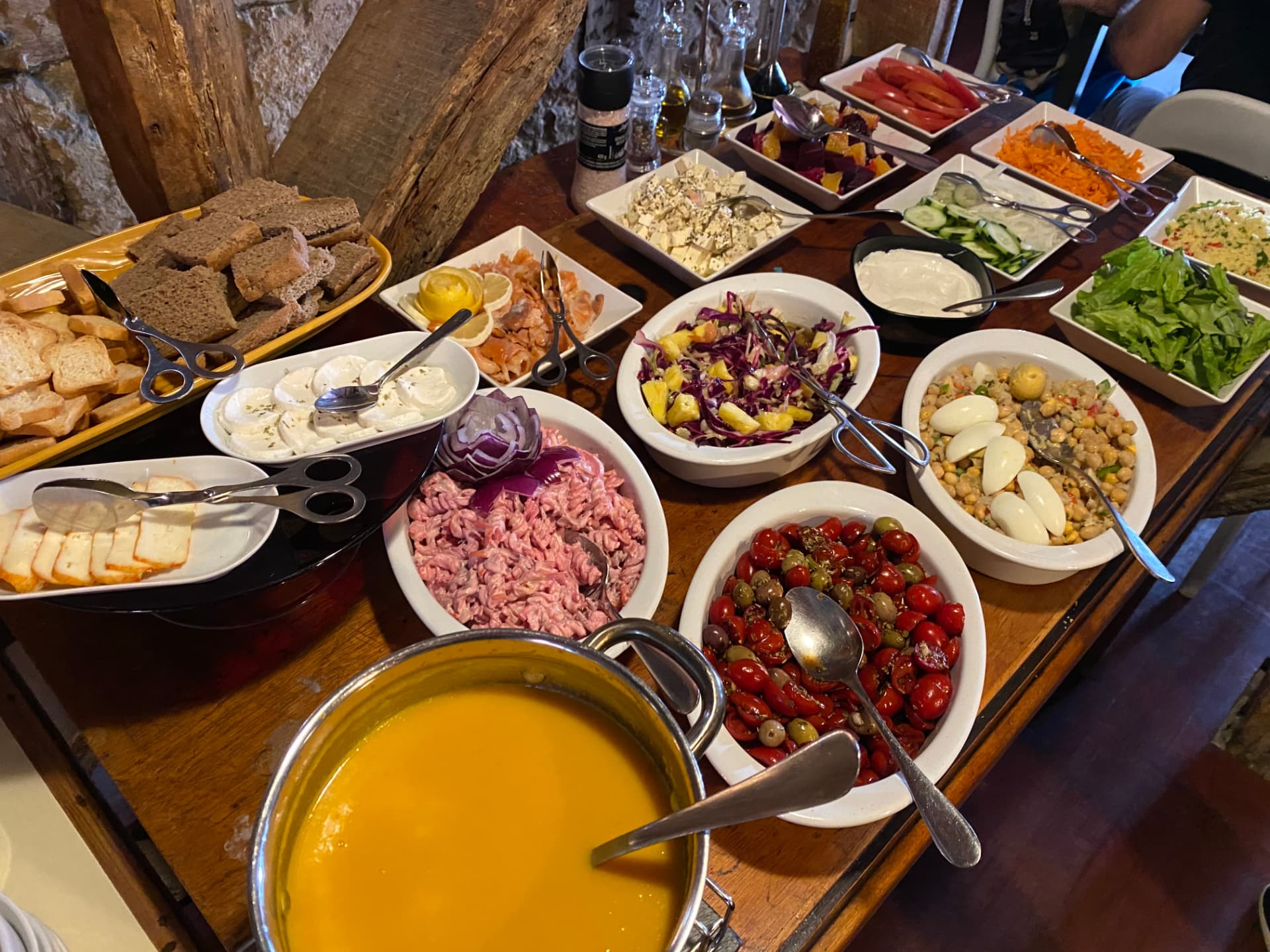 A wooden table covered with bowls of salad and soup