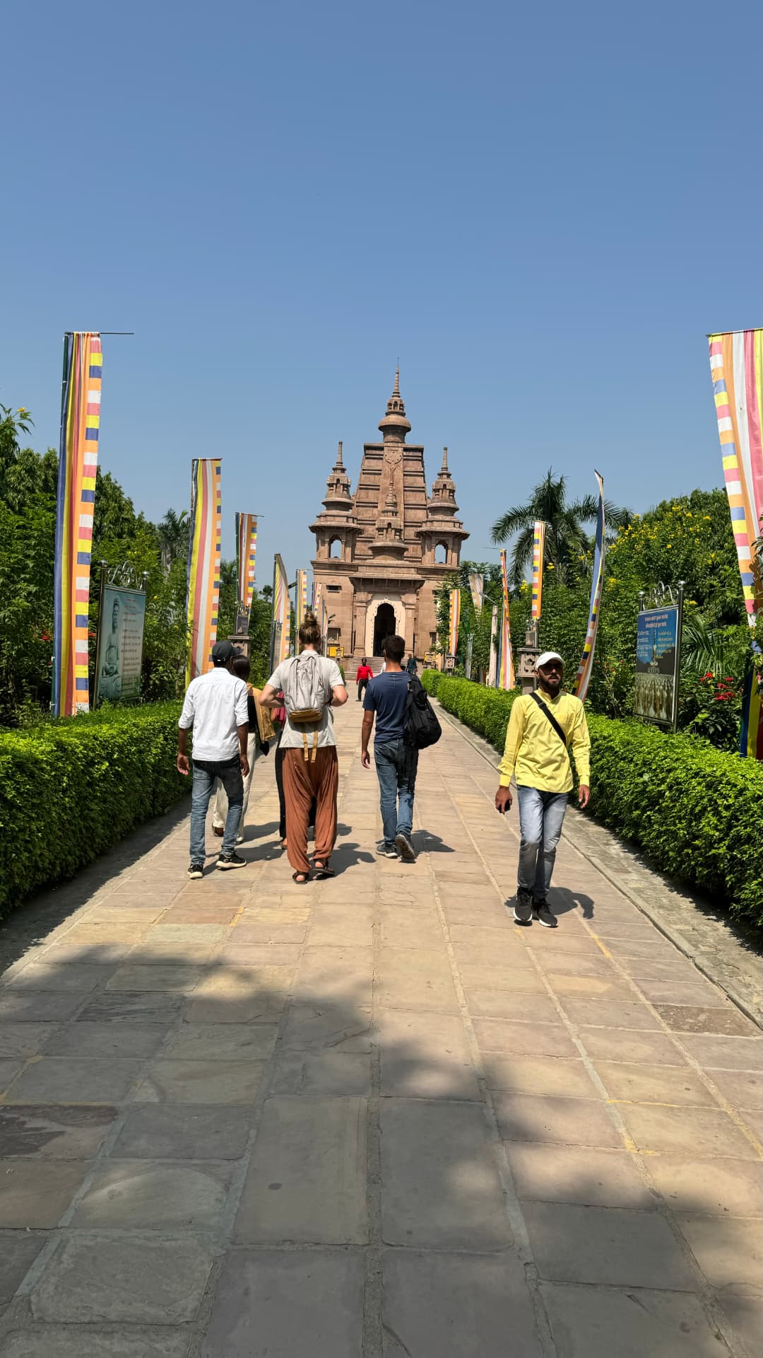 Pilgrims follow the flag-lined path toward the temple. — Sarnath, Uttar Pradesh, India.