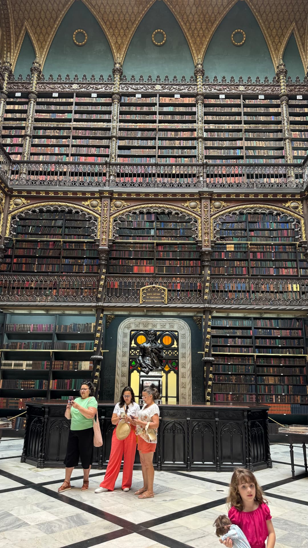 Tall book-lined interior of the Portuguese Reading Room with visitors below