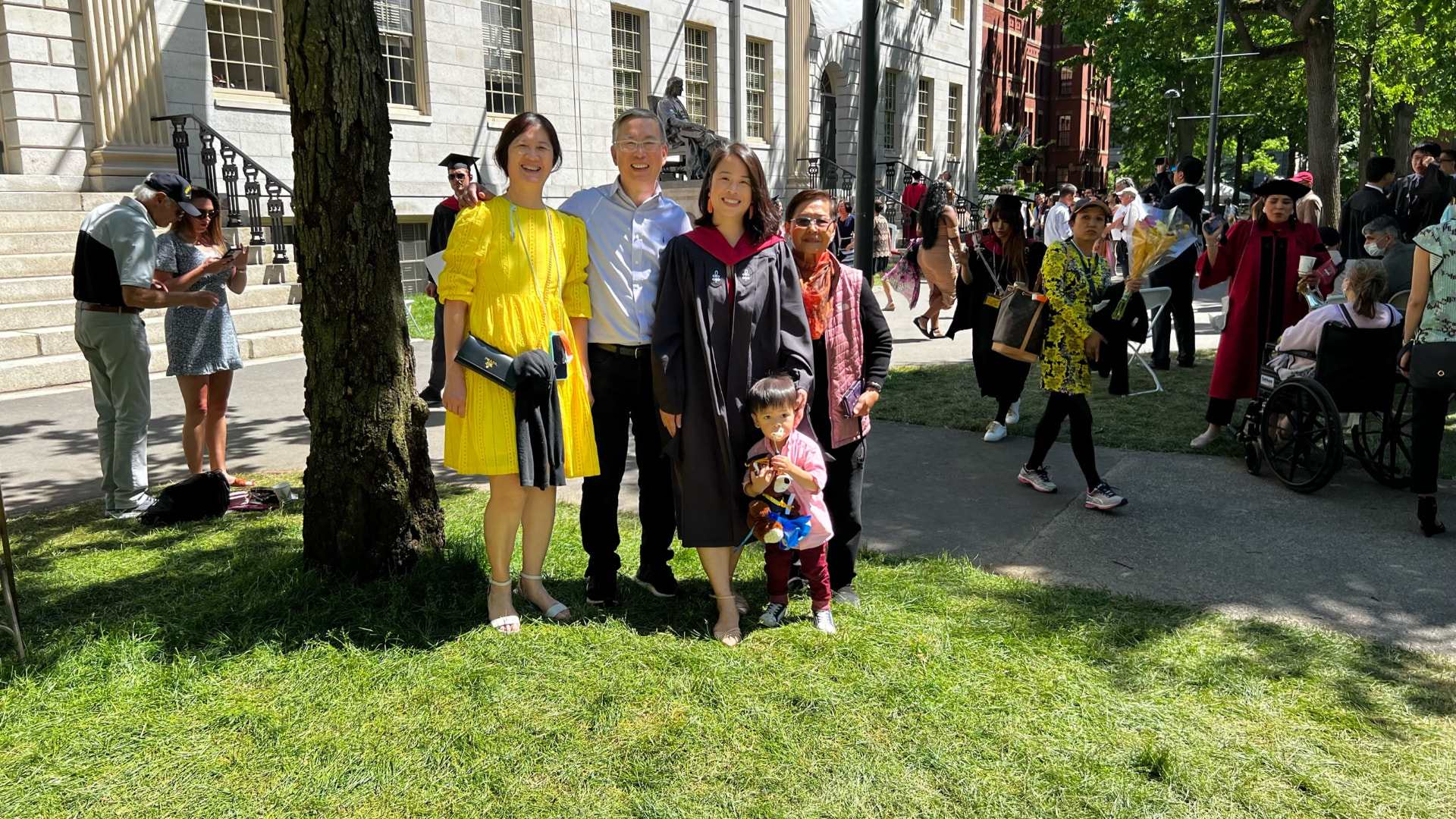 Family gathered on the grass near University Hall and the John Harvard statue