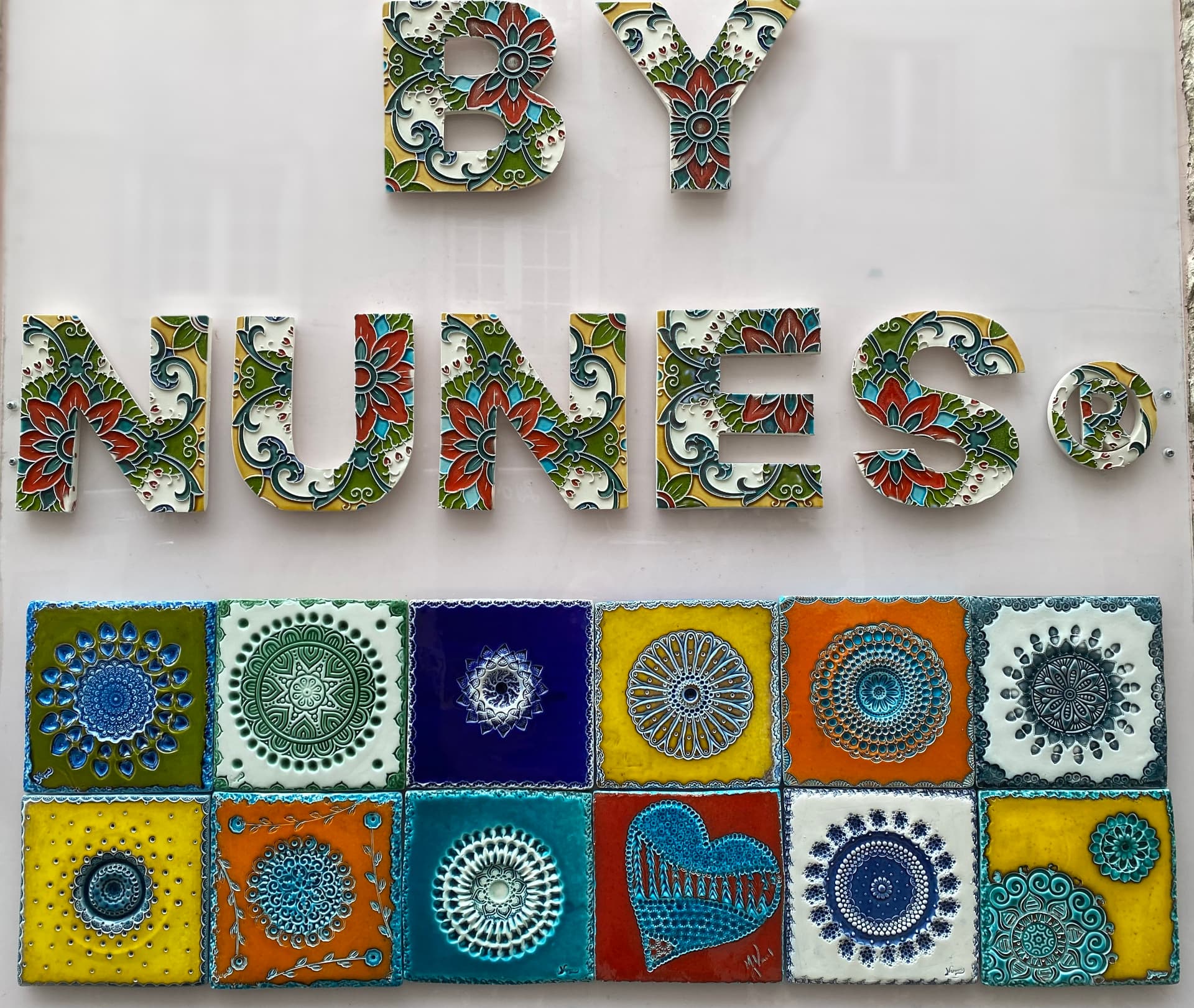 A tiled wall beneath a sign reading By Nunes