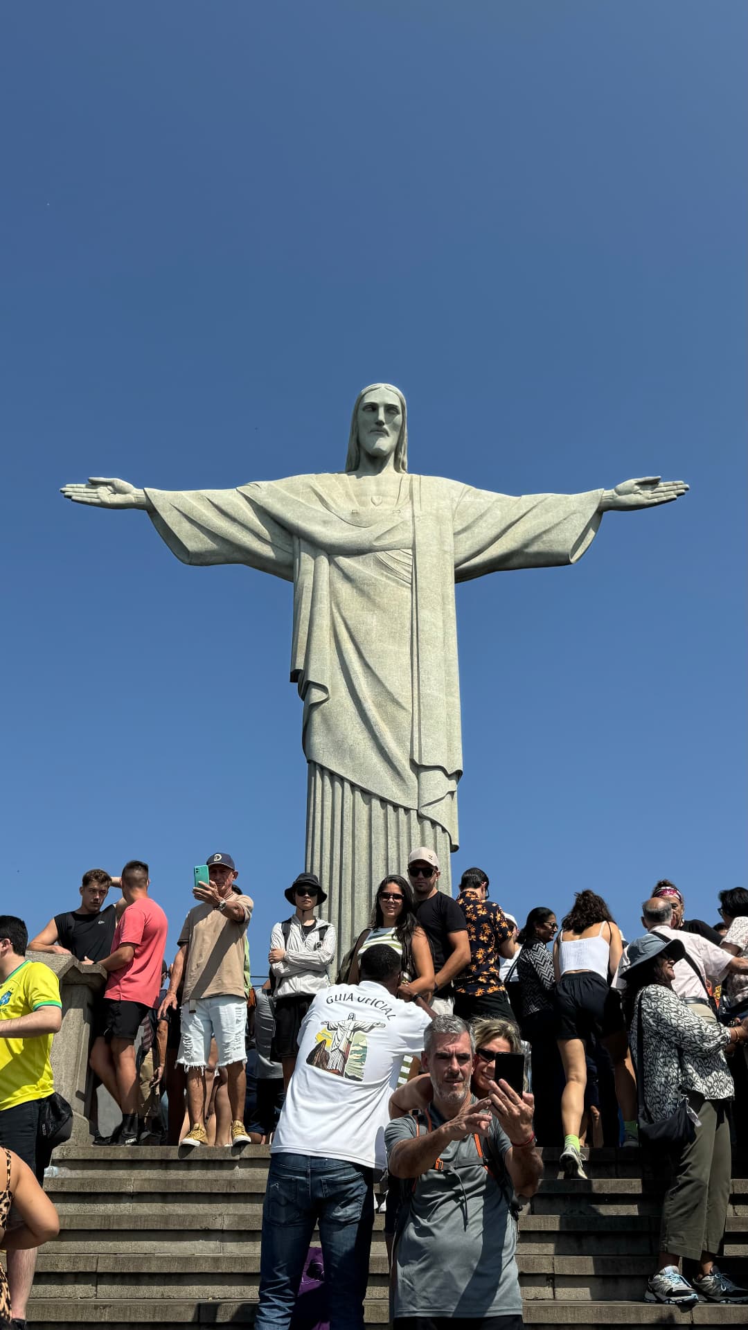 Visitors gathered beneath Christ the Redeemer under a clear sky