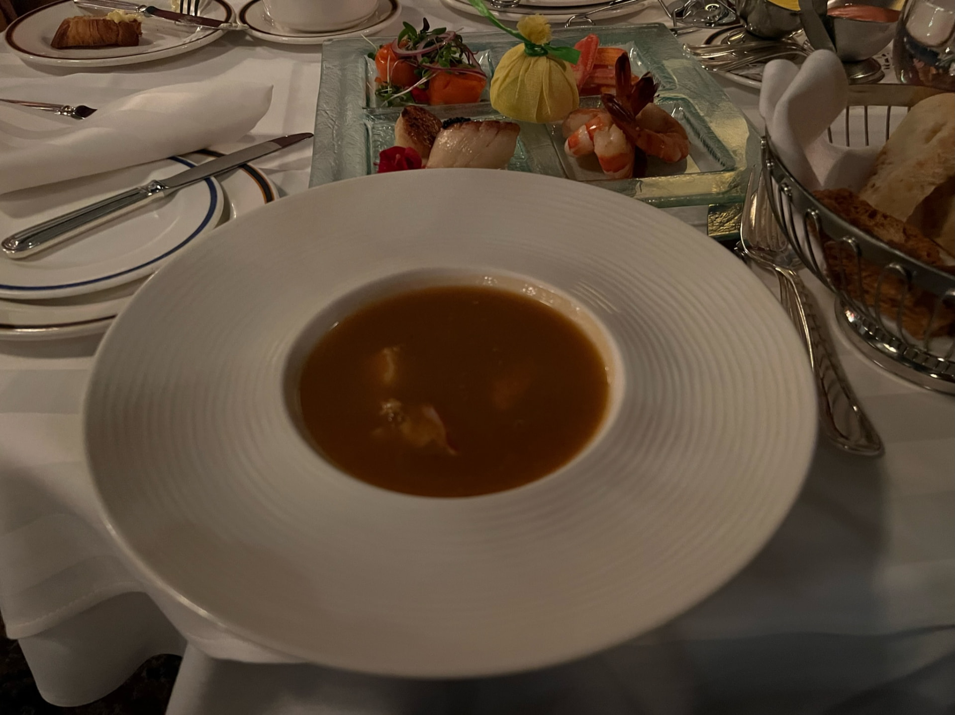 Soup and seafood courses on a white-clothed table