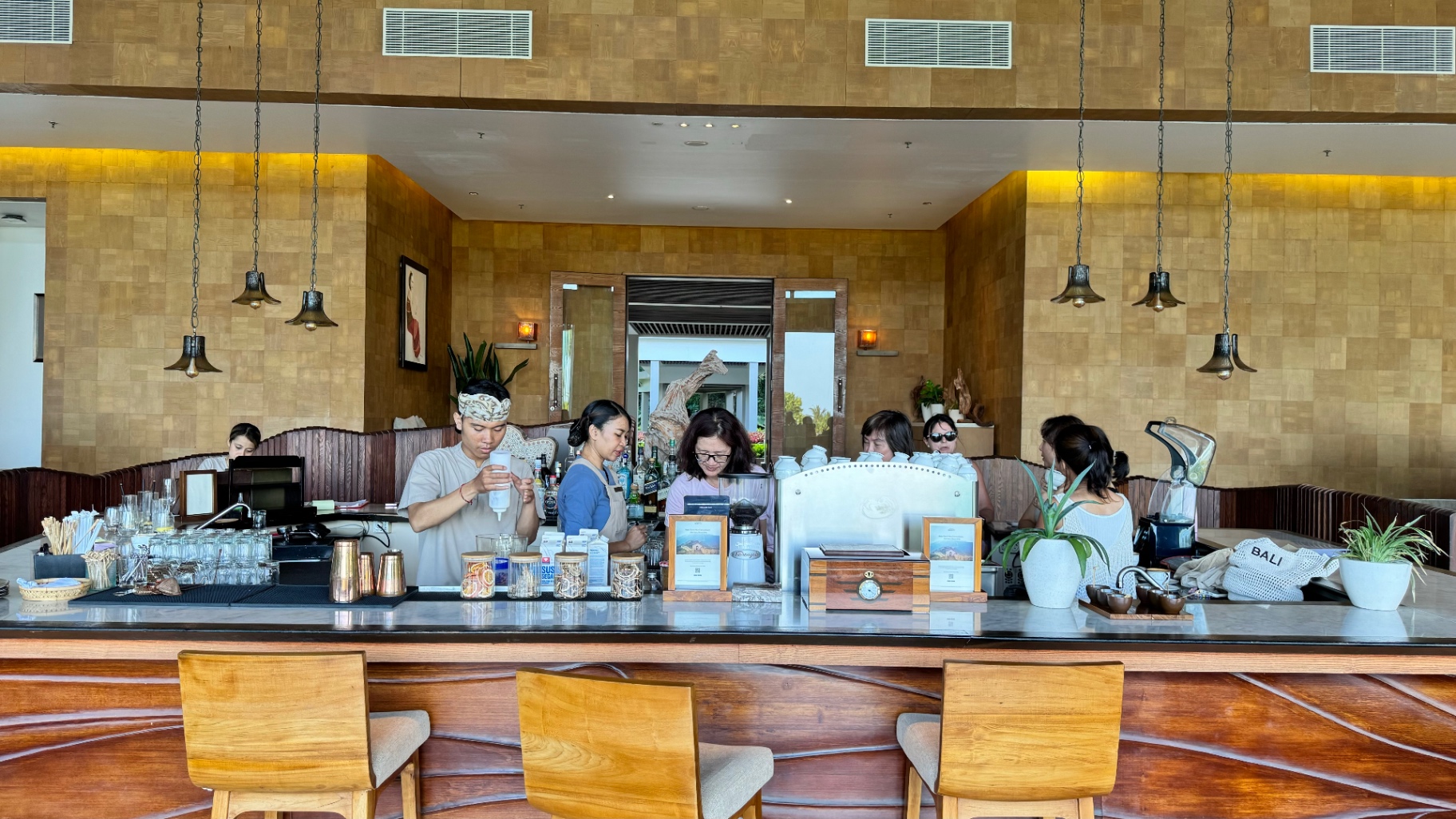 Resort bar with timber stools and staff preparing drinks