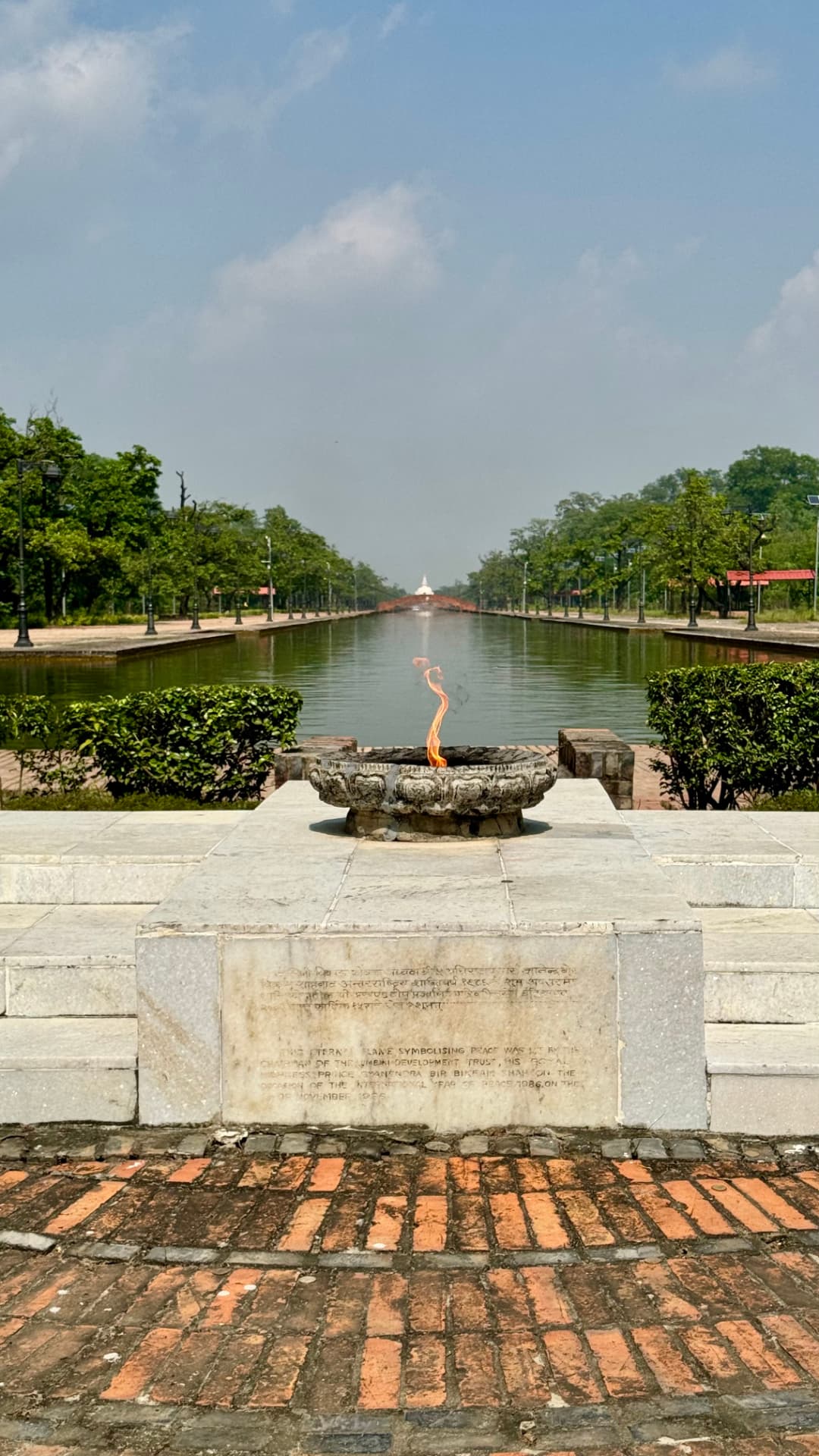A long view down the canal, framed by trees and a stone terrace. — Lumbini, Nepal.