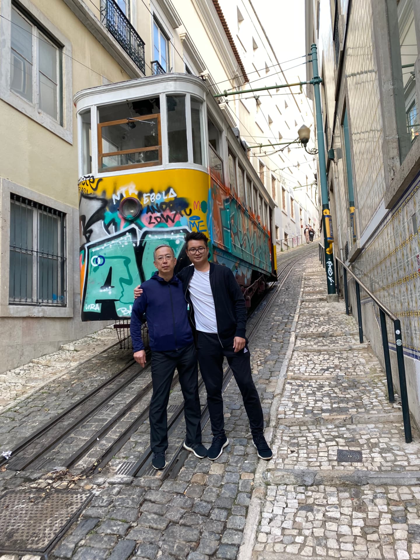 Two companions standing in front of a graffiti-covered tram