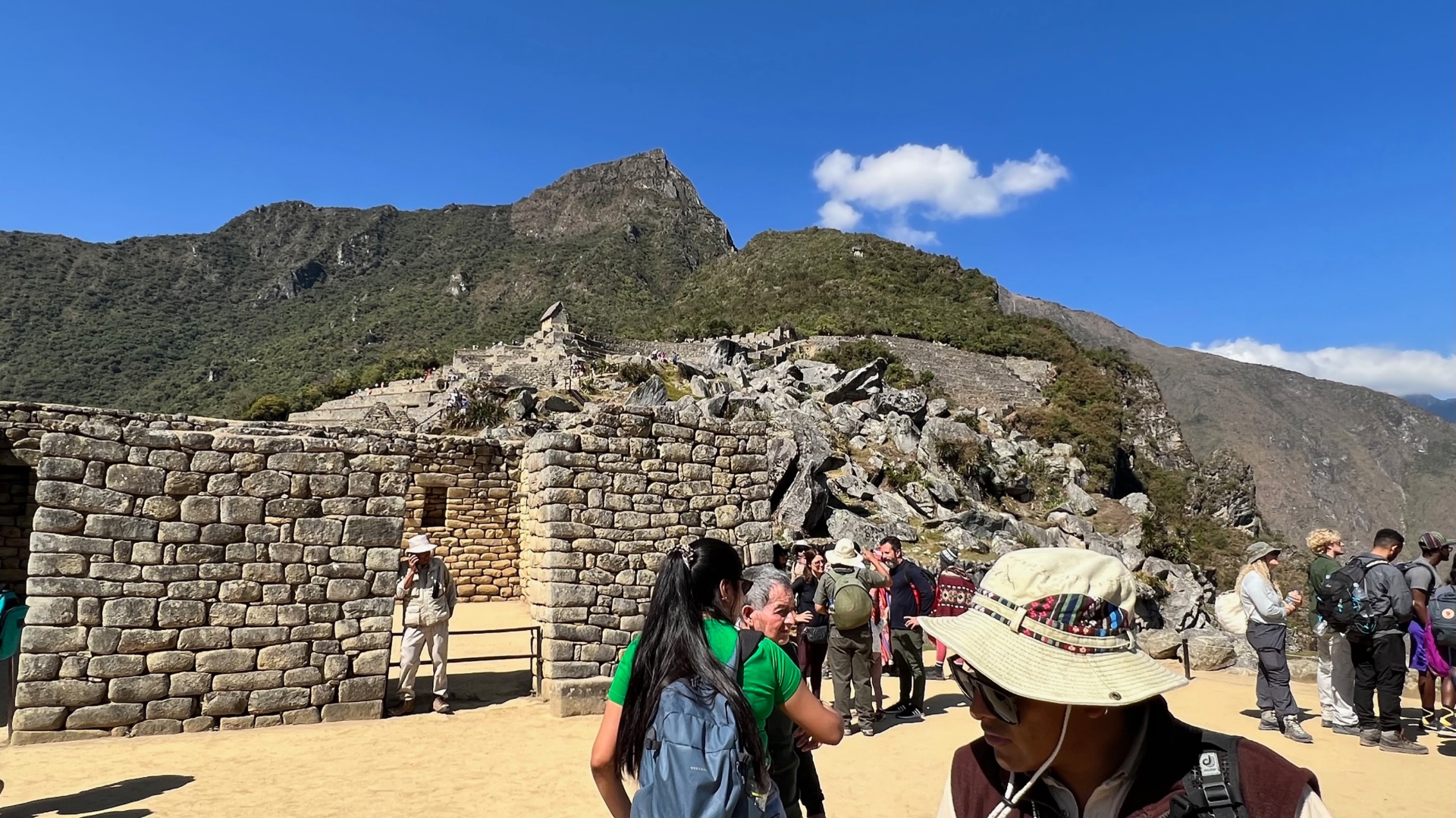 Visitors walking among stone buildings with the upper terraces beyond