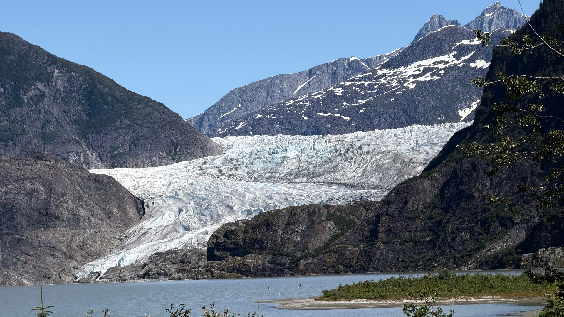 Mendenhall Glacier framed by rugged mountains, blue sky and water
