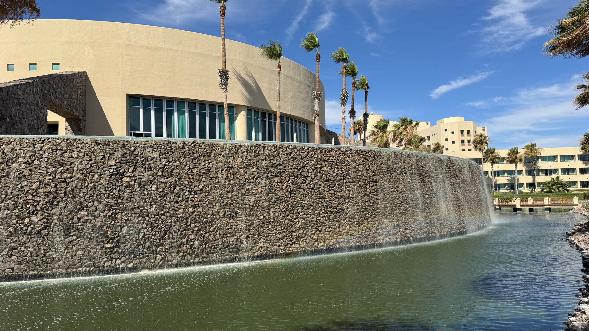 Curved stone wall with water cascading into a lagoon