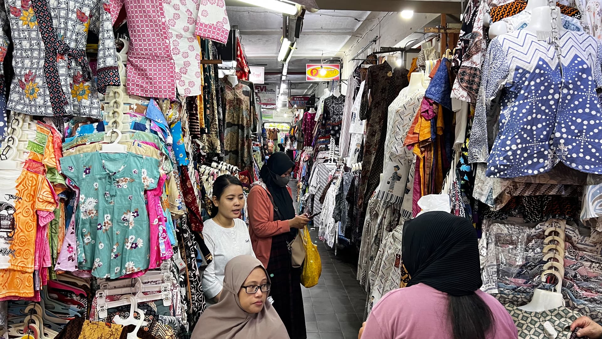 Clothing stalls and shoppers in a Yogyakarta market