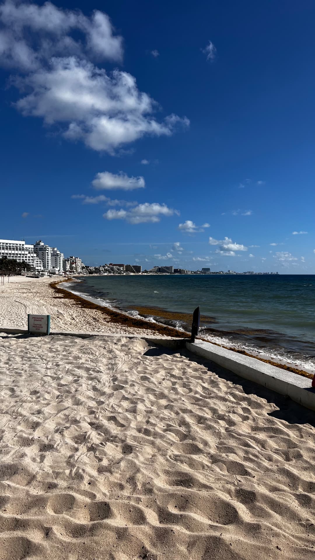White sand beach curving along Cancún beneath a deep blue sky