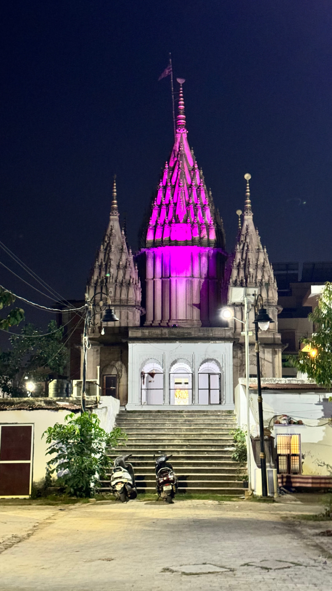 A temple spire illuminated in vivid pink against the night sky. — Varanasi, Uttar Pradesh, India.