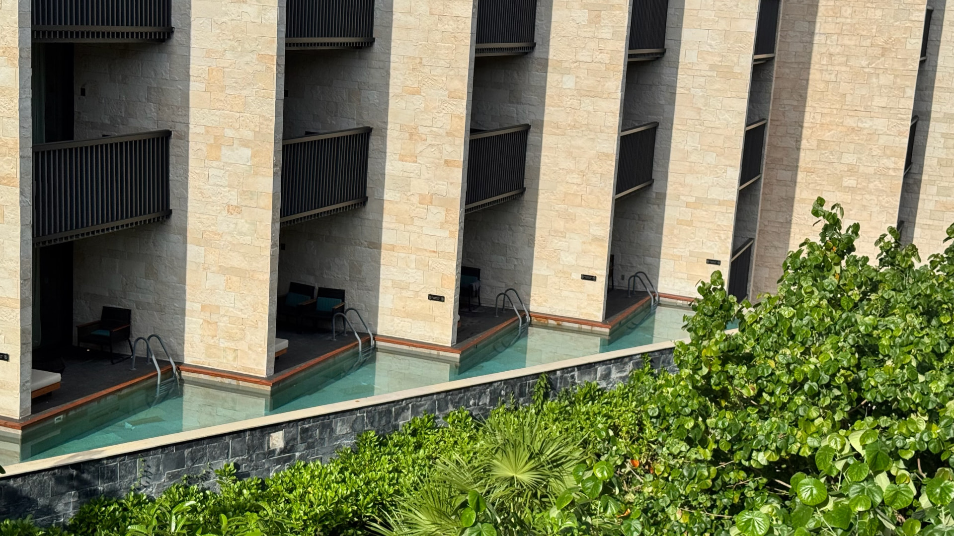 Swim-up rooms along a pale stone hotel wing