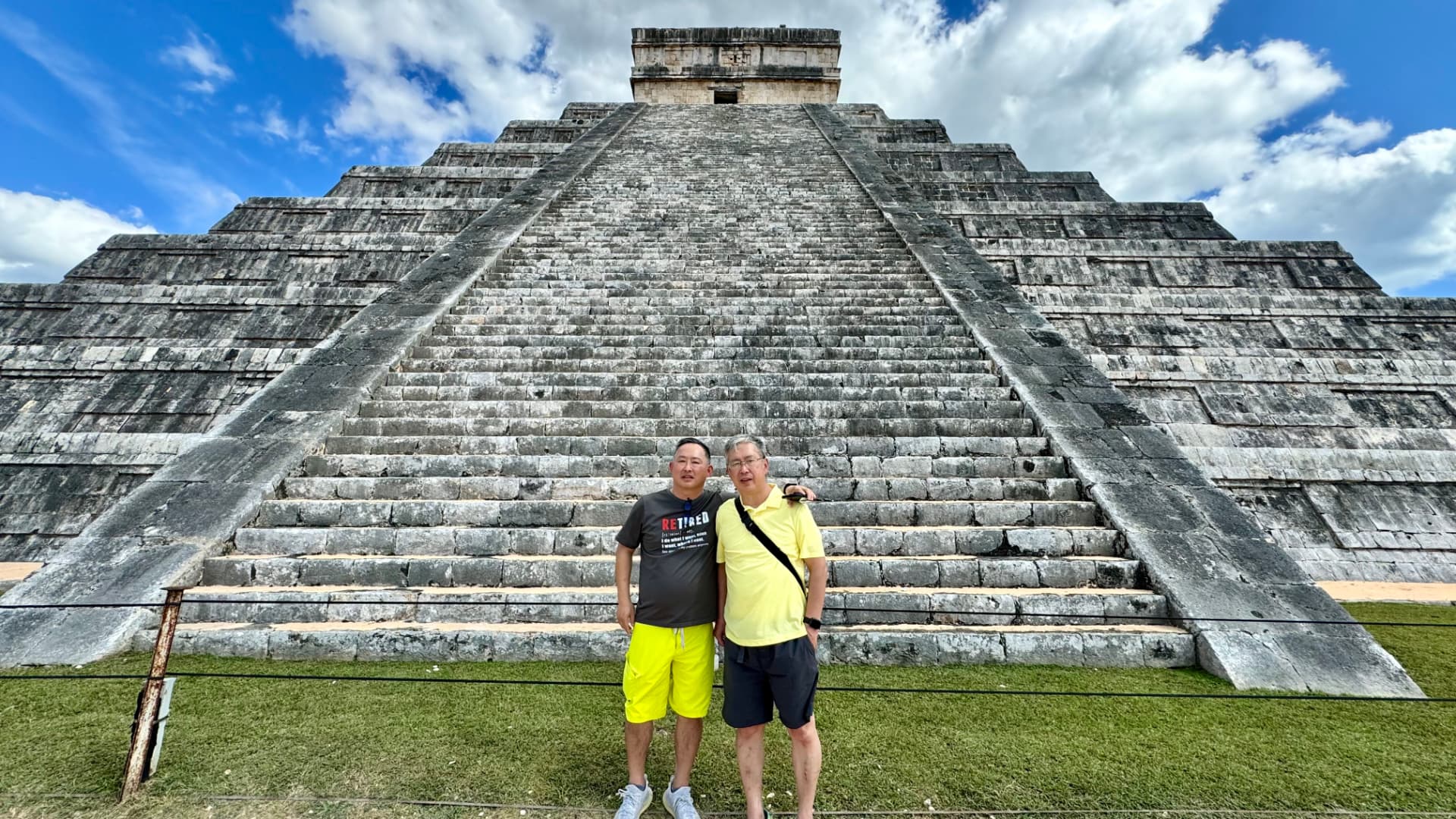 Two travelers standing together at the foot of El Castillo
