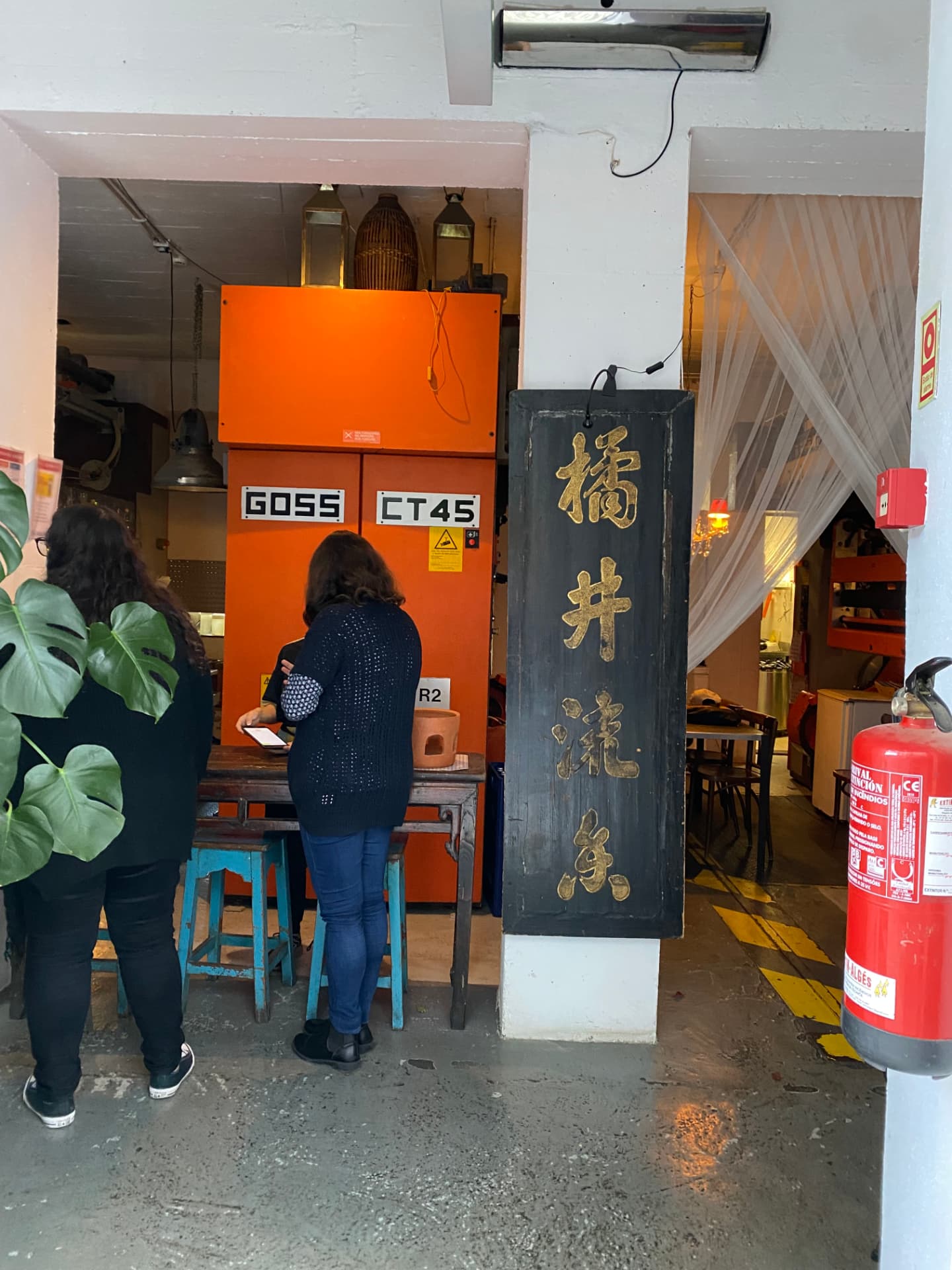 Guests waiting inside a small restaurant with an orange wall