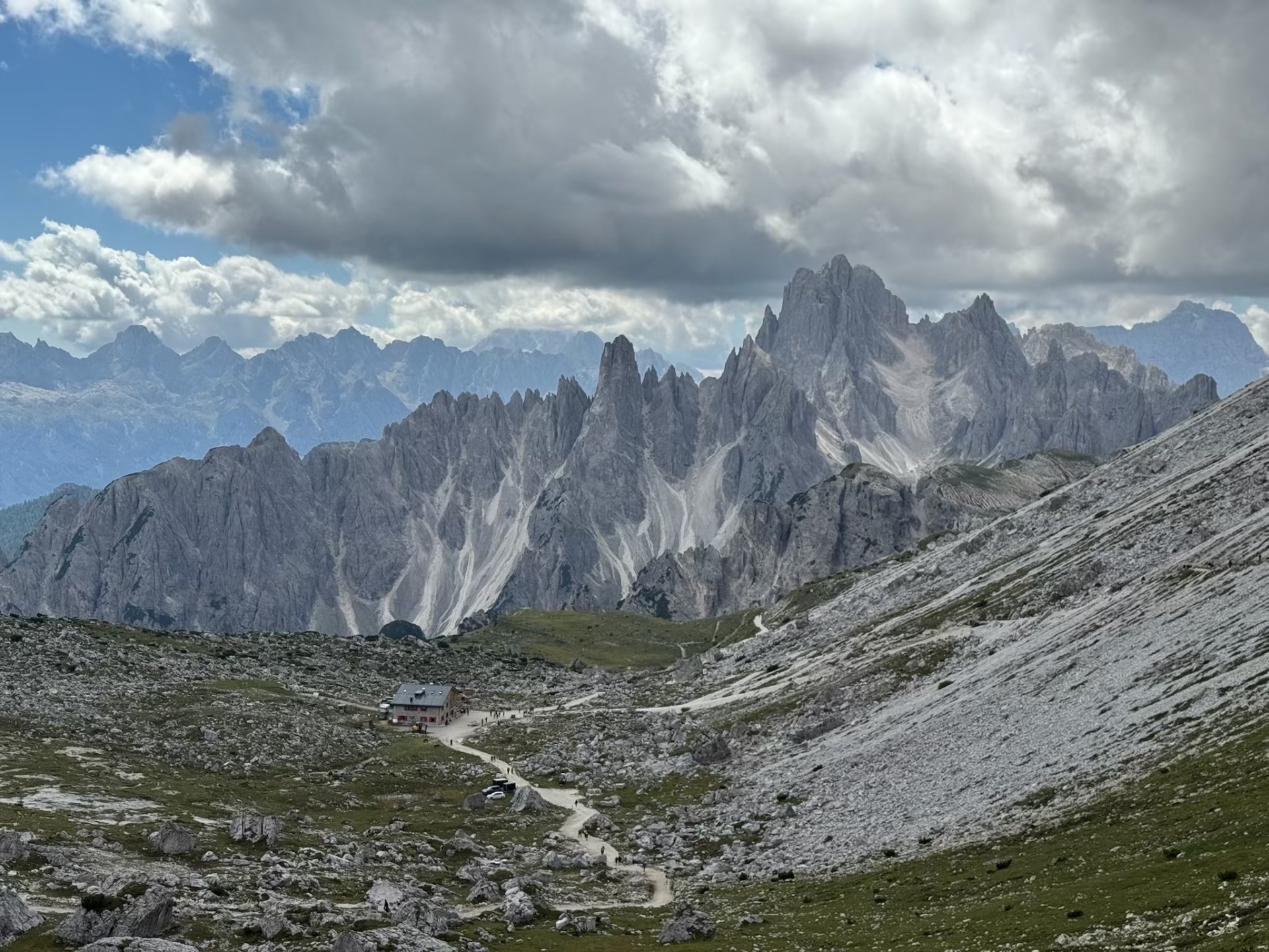 Rocky mountain trail leading toward a refuge beneath jagged Dolomites peaks
