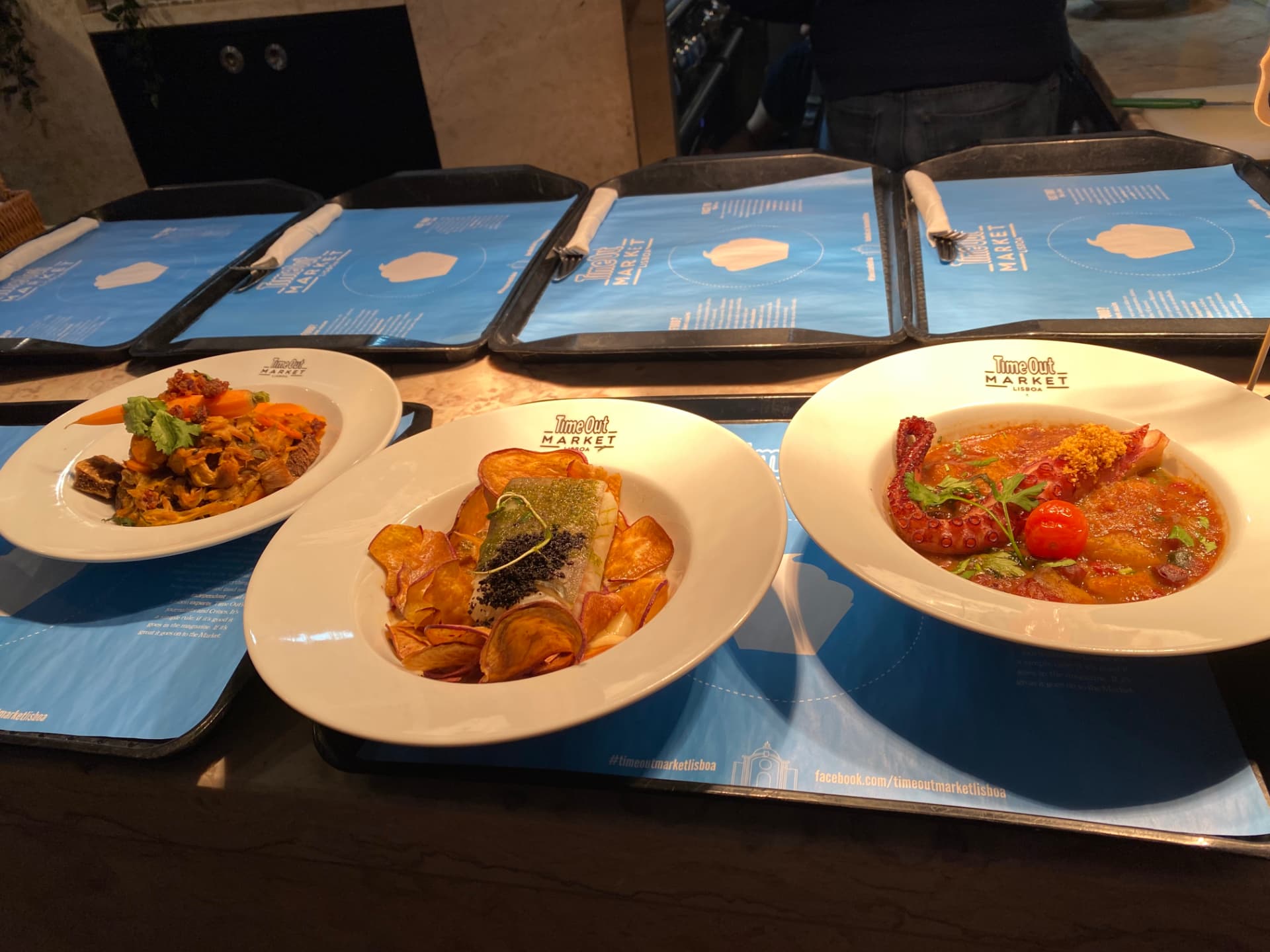 Three plates of food served on blue menus at a restaurant