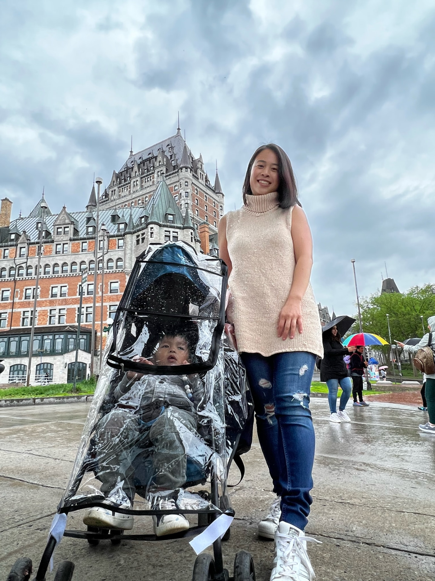 Mother and child with a rain-covered stroller before Château Frontenac
