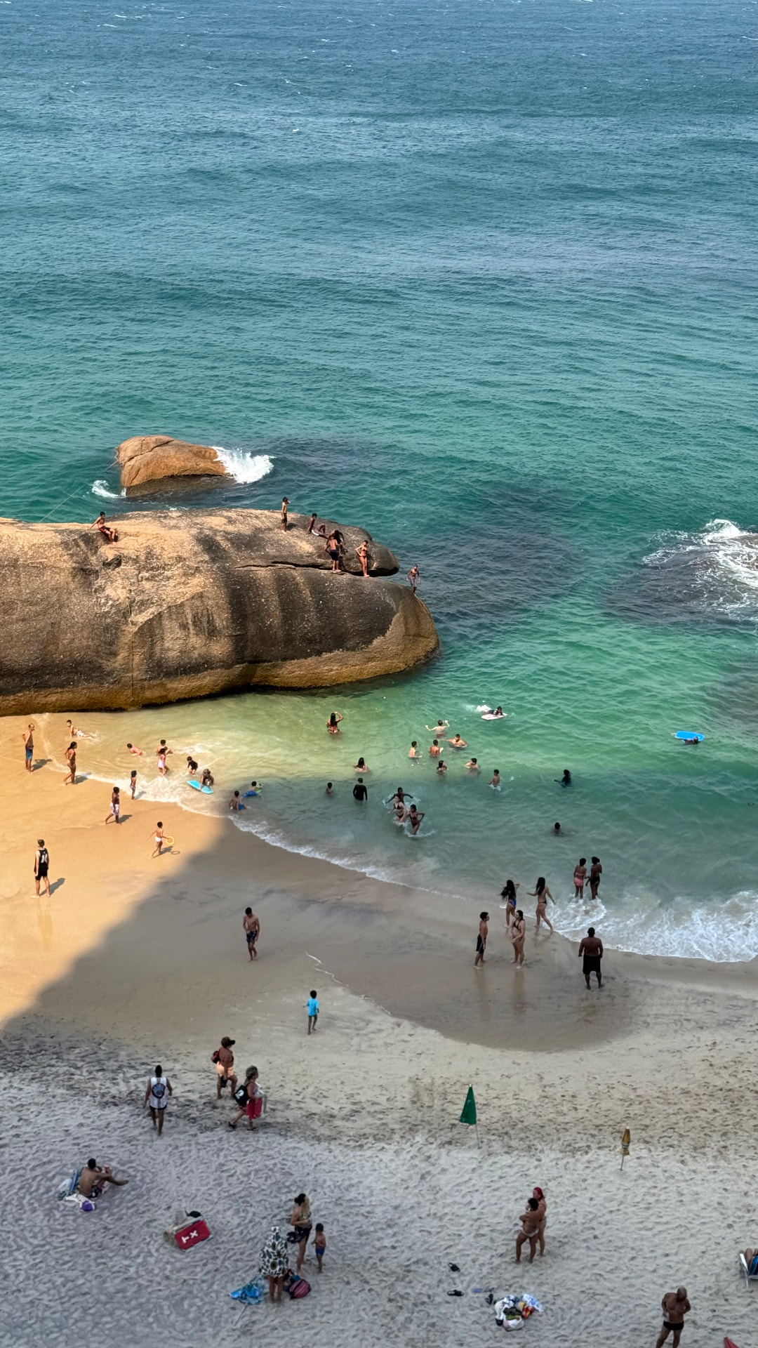Swimmers gathered around a small turquoise cove and broad coastal rocks in Rio