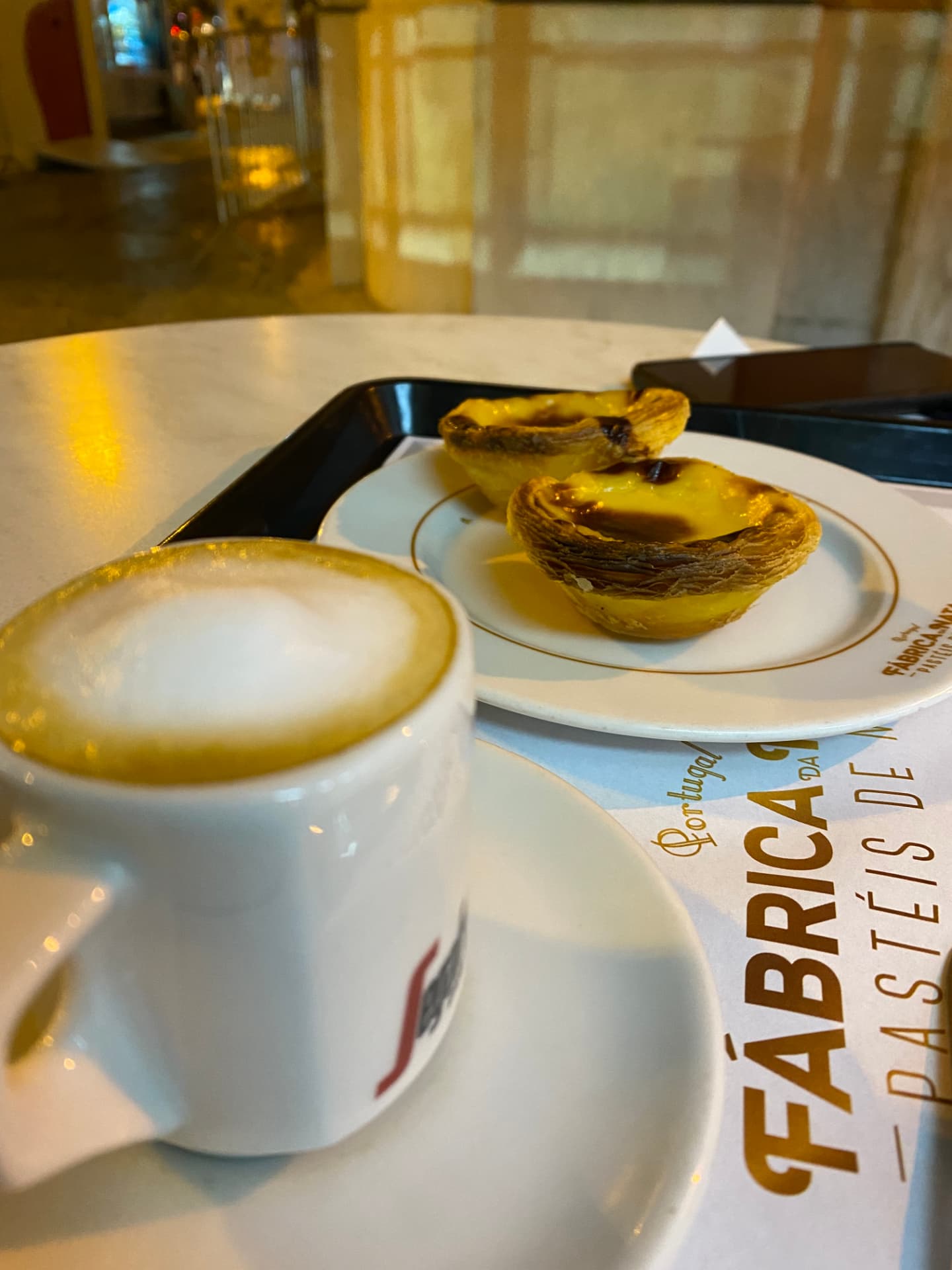 A cup of coffee with two pastries on a café table