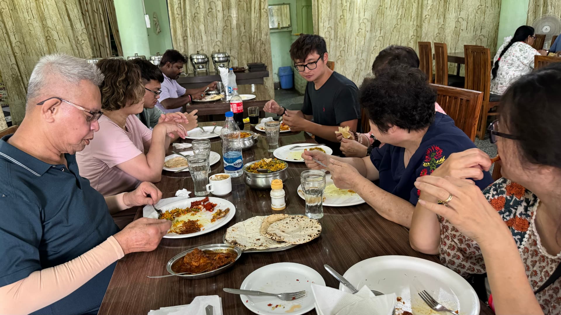 Our pilgrimage group shares a meal around a long table. — Nalanda, Bihar, India · Patna chapter.