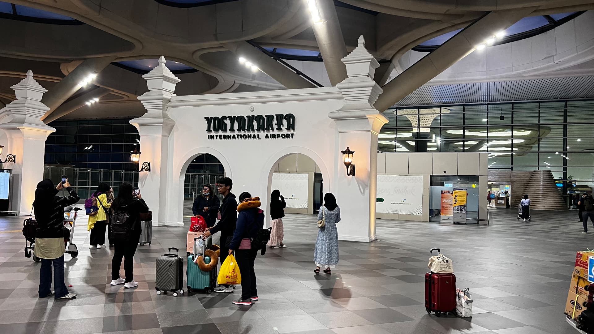 Travelers beneath the Yogyakarta International Airport sign