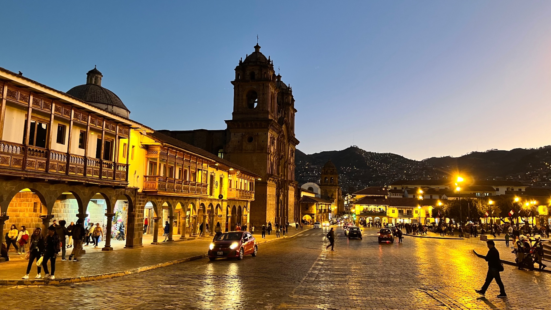 Illuminated colonial arcades and church tower in Cusco at dusk