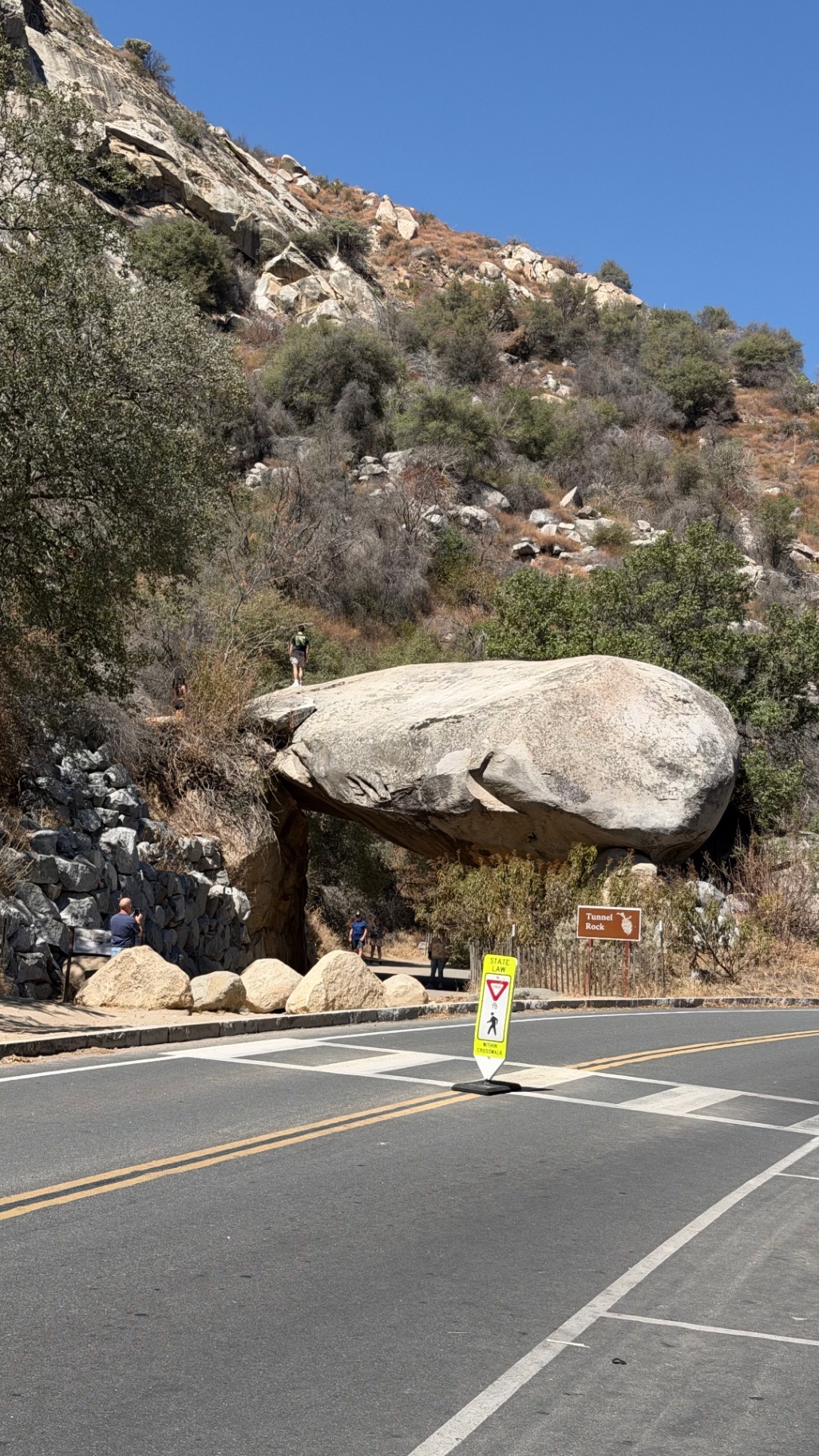 Tunnel Rock, a huge granite boulder resting over the old road, with people standing on top