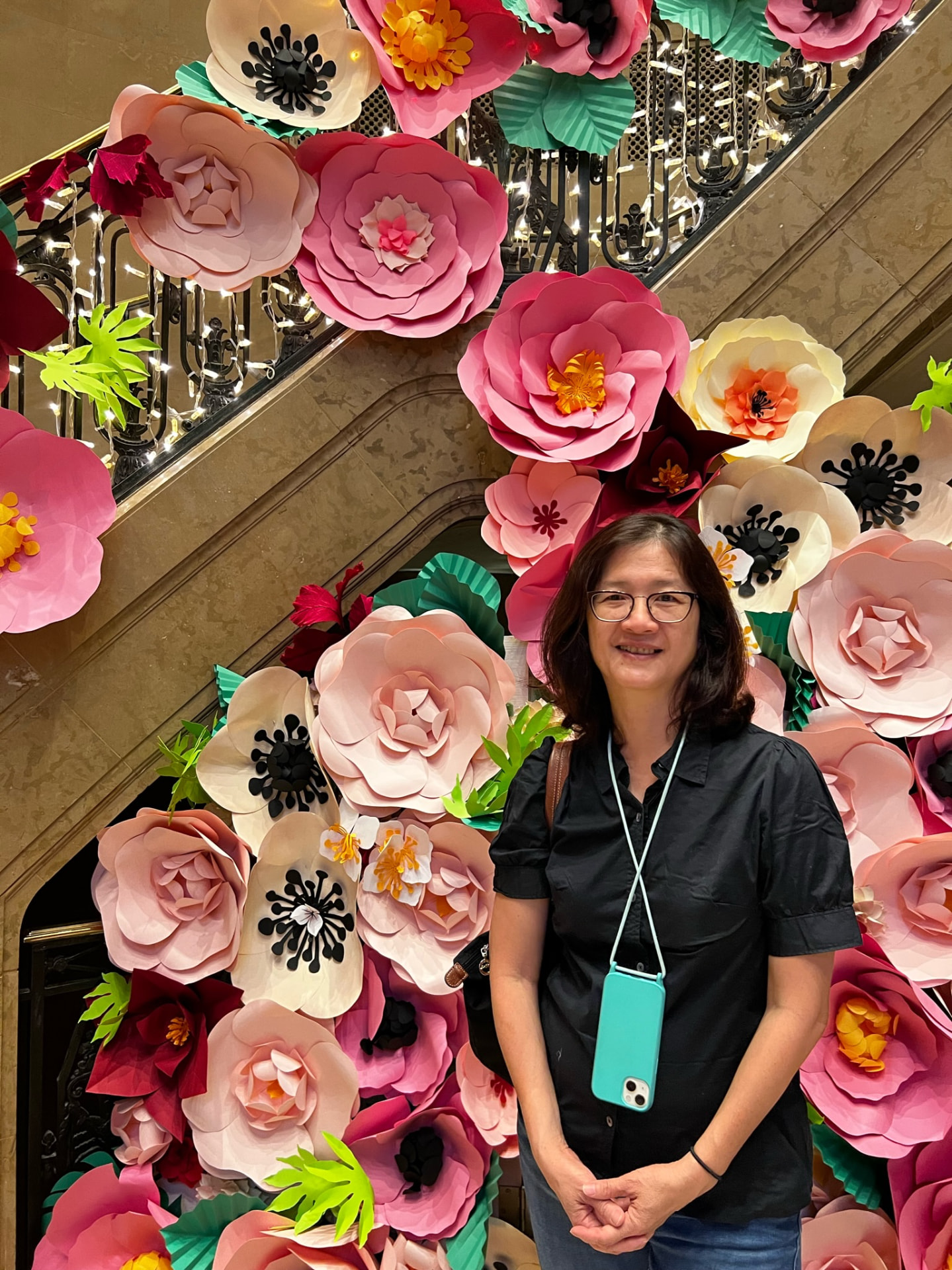 Woman standing before a bright installation of oversized paper flowers