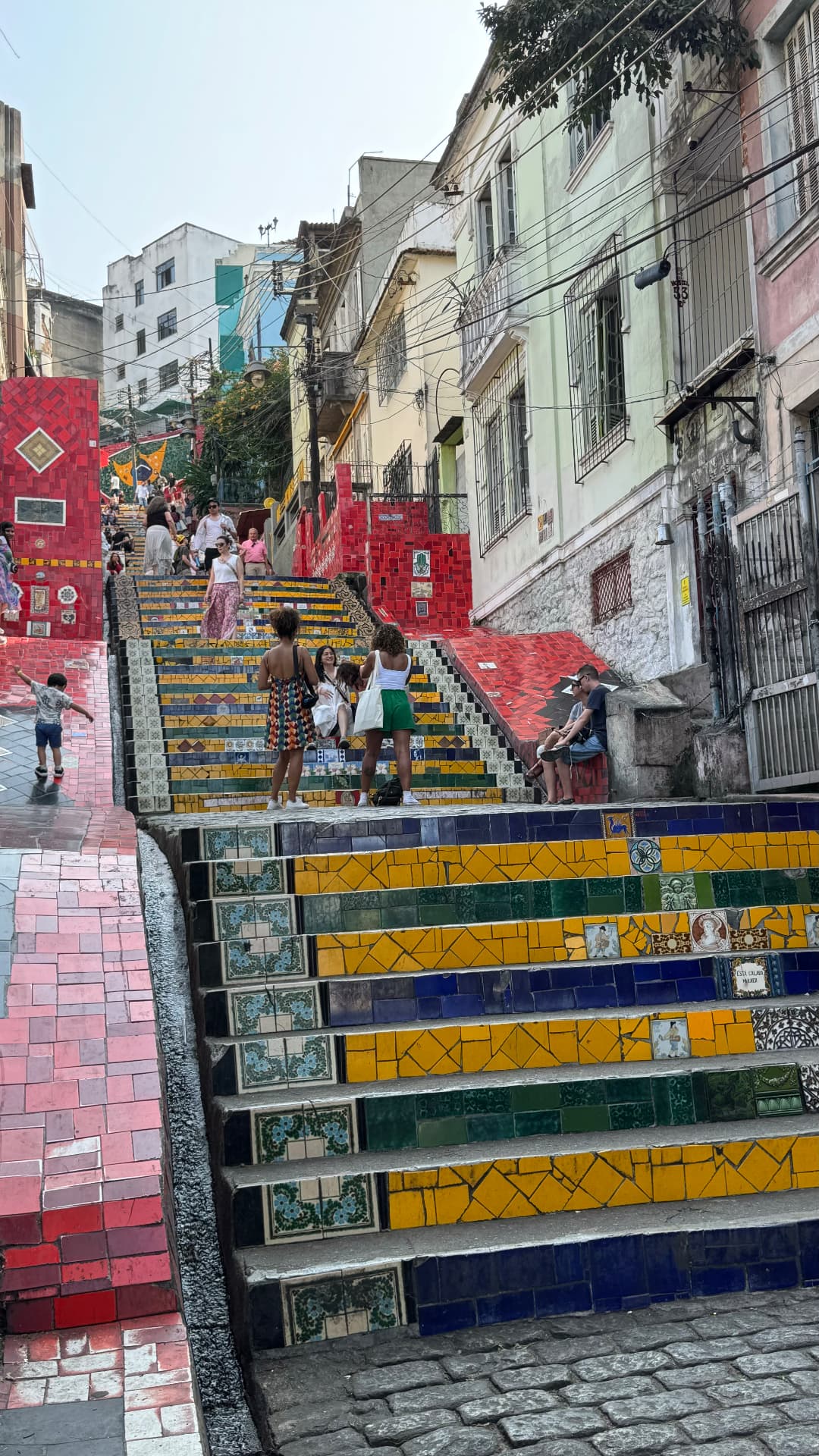 Visitors climbing the brightly tiled Selarón Steps between colourful buildings