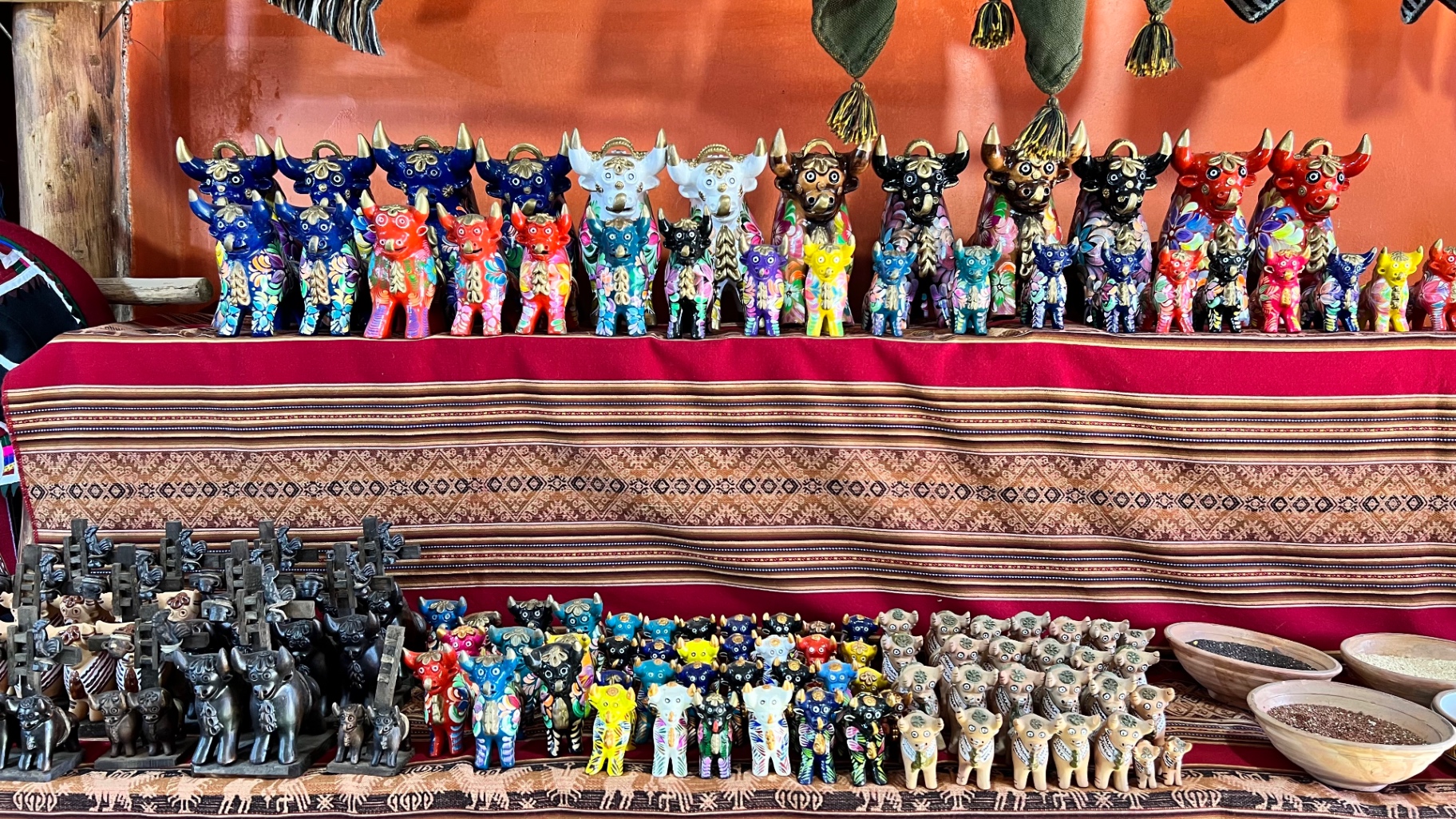 Rows of colourful handmade figures displayed on woven textiles