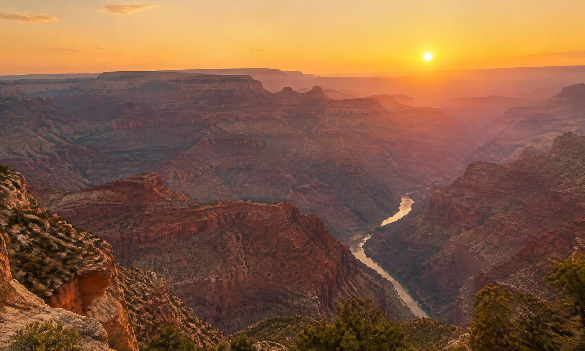 Layered red rock cliffs of the Grand Canyon at golden hour, fading into purple haze